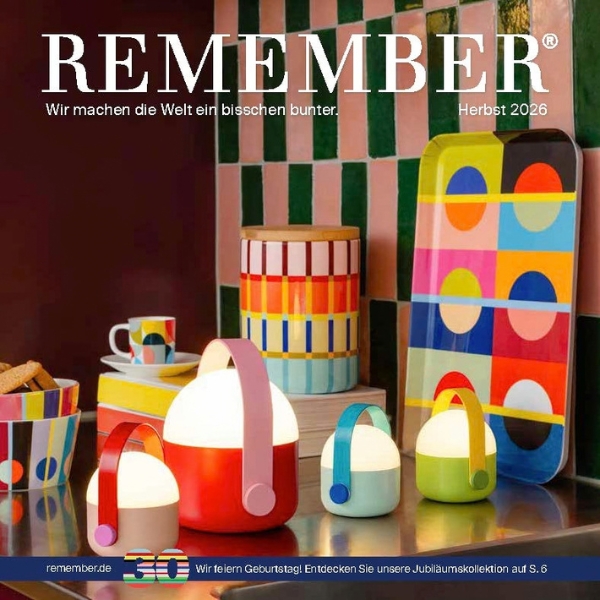 Scena colorata con prodotti di design su una superficie scura, davanti a piastrelle a quadretti rosa e verdi. Lanterne in rosso, azzurro e verde lime accanto a barattolo a righe, vassoio, portabiscotti e tazza. Pubblicità per REMEMBER.