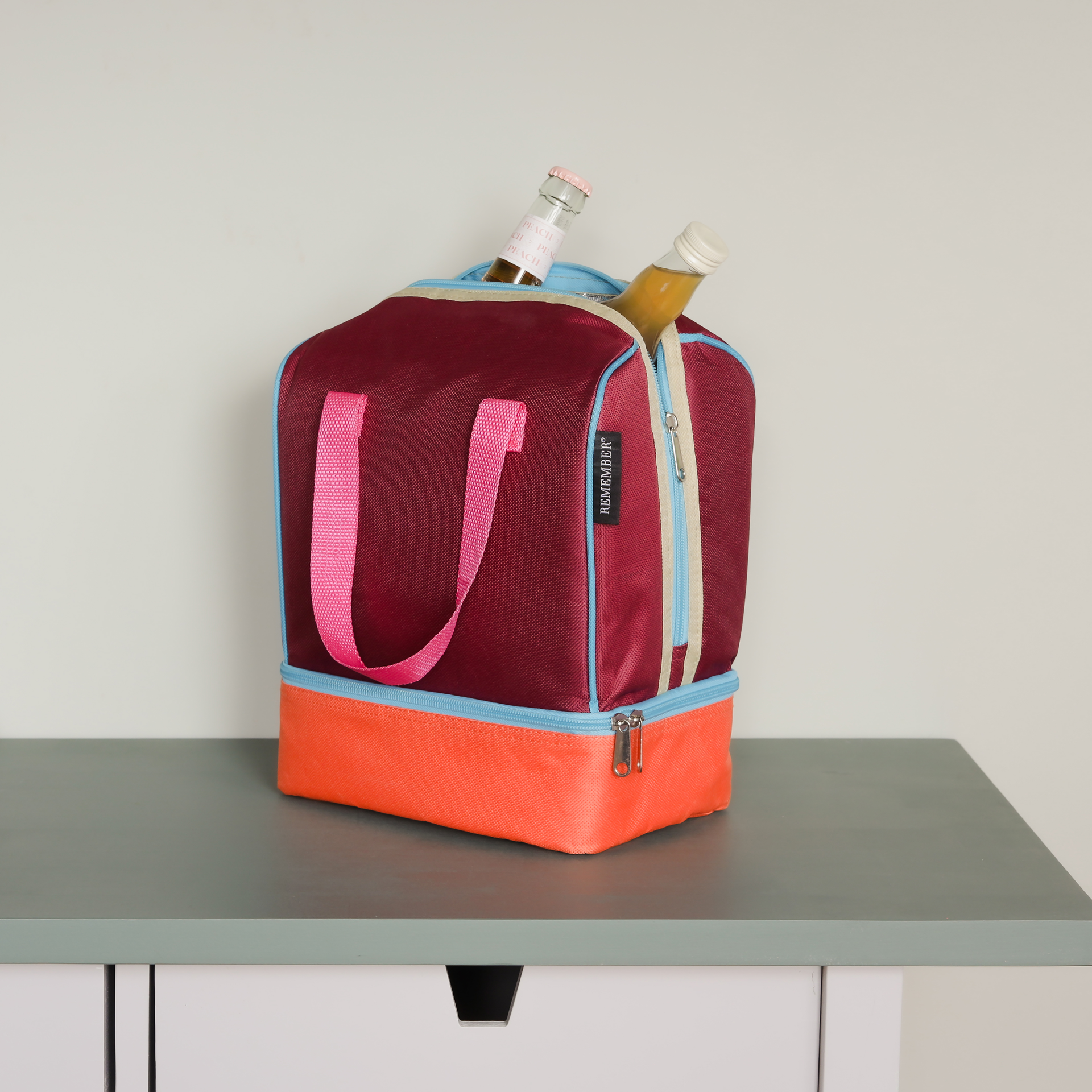 Zweifarbige Lunch-Kühltasche 'Telli' mit Trageriemen und zwei Reißverschlusstaschen. In der oberen Tasche stehen zwei Flaschen.