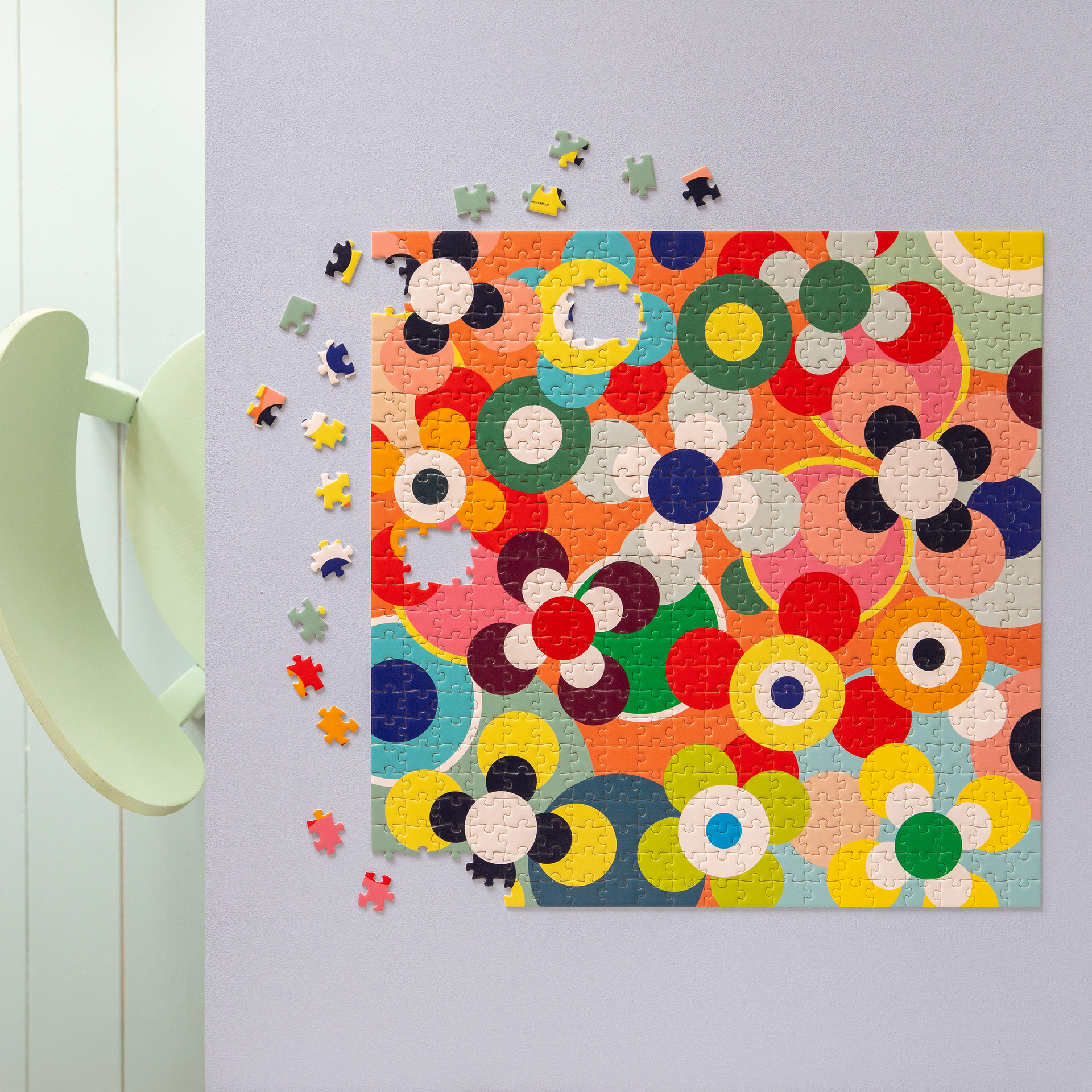 Ein fast fertiges Puzzle mit Blumenmuster in bunten Farben liegt auf einem Tisch. Einige Puzzleteile liegen daneben.