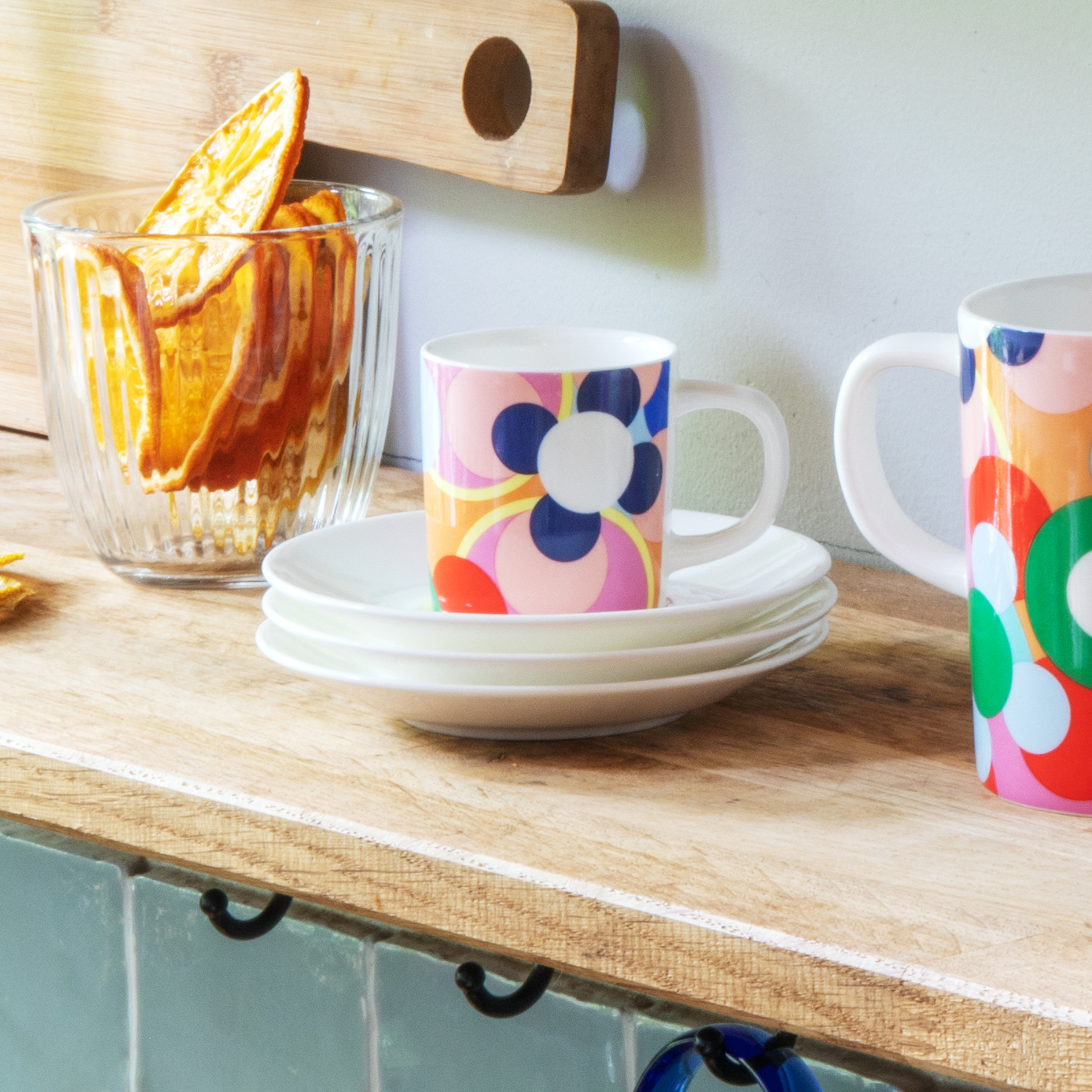 Espressotasse mit Unterteller: Weißes Porzellan mit farbenfrohem, abstraktem Blütenmuster in Pink, Blau, Rot und Schwarz.