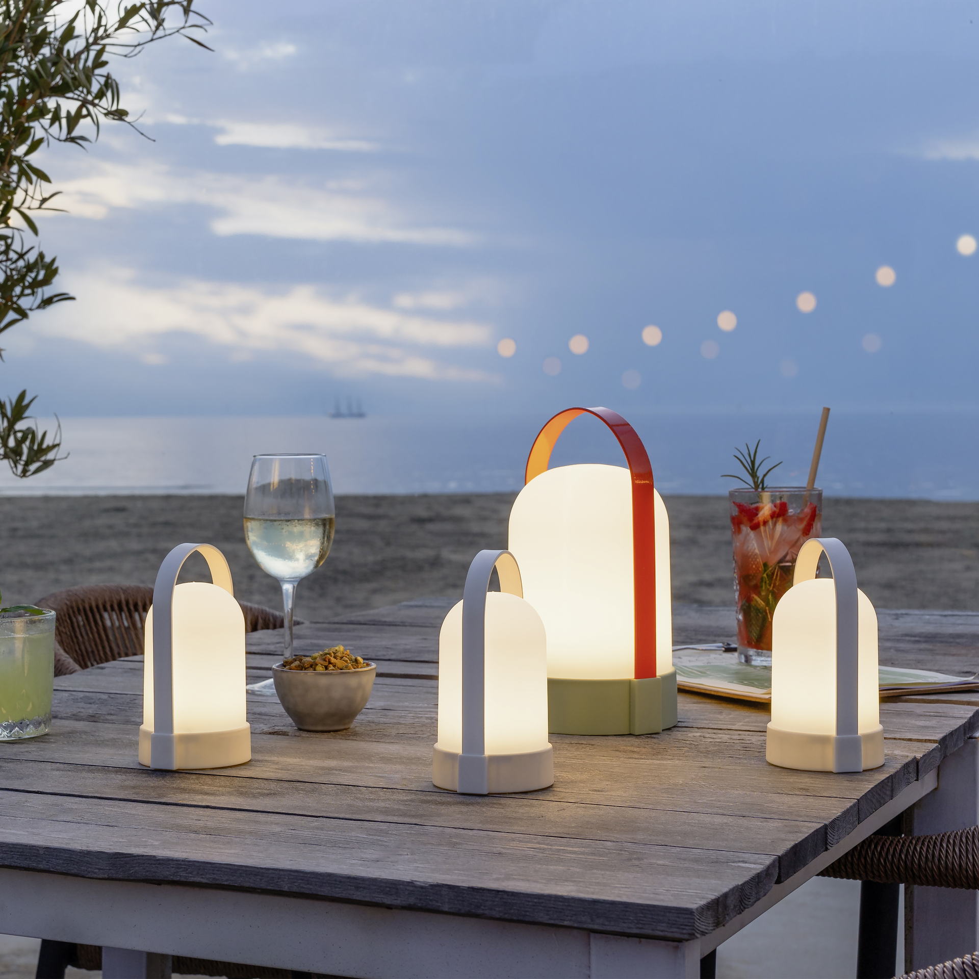 Drei weiße URI Piccolo Leuchten im Set. Jede Lampe verfügt über einen Tragebügel und emittiert warmweißes Licht. Die LED-Leuchten sind vor einem weißen Hintergrund arrangiert.