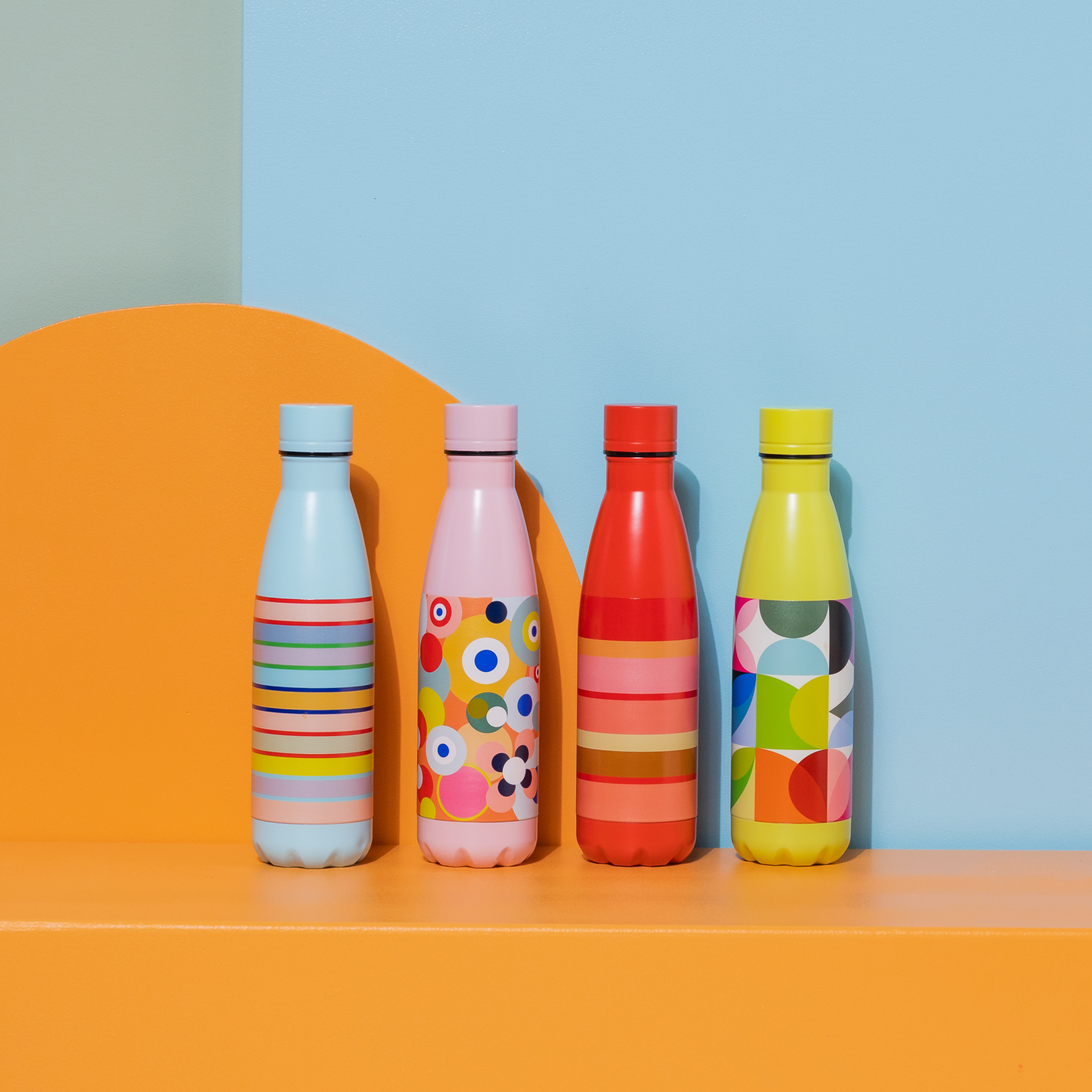 Gelbe Solena Edelstahl-Trinkflasche mit farbigem geometrischem Muster. Links davon Logo mit Zahl 30 in bunten Streifen auf blauem Grund.