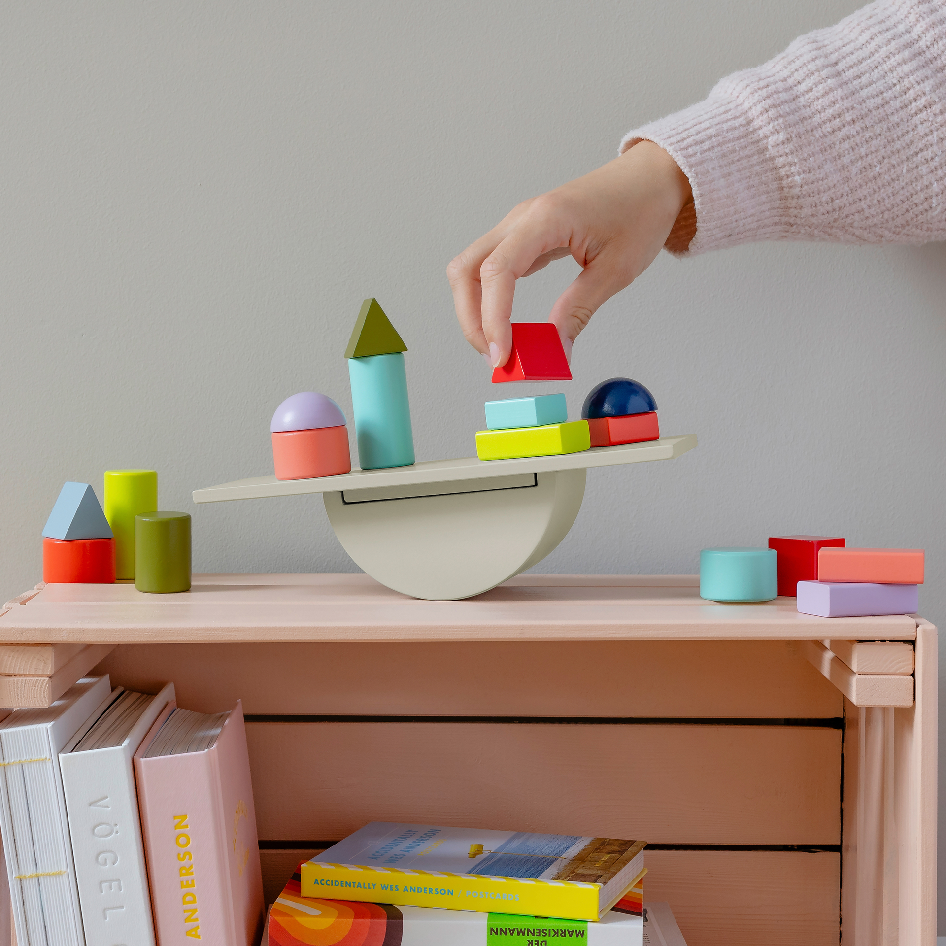 Verpackung des Balancespiels 'Tivoli' mit Wippe und bunten Holzbausteinen unterschiedlicher Formen. Einige Bausteine liegen daneben, andere stehen auf der Wippe.