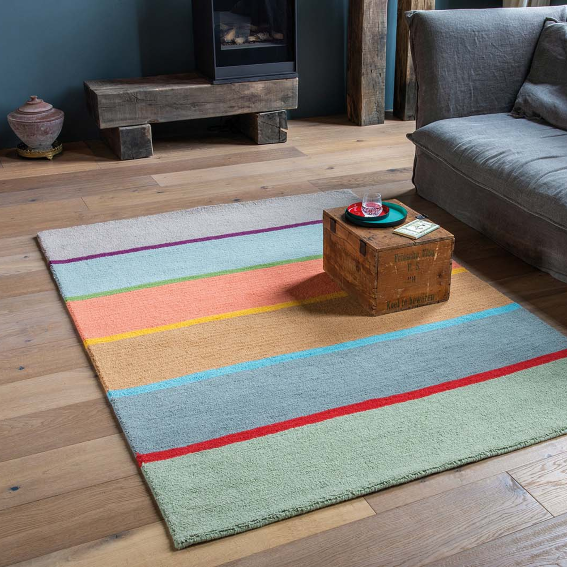Tappeto rettangolare in lana 'Cambridge' a righe verticali nei colori grigio, viola, blu, verde, rosa, giallo, marrone, rosso e verde chiaro.