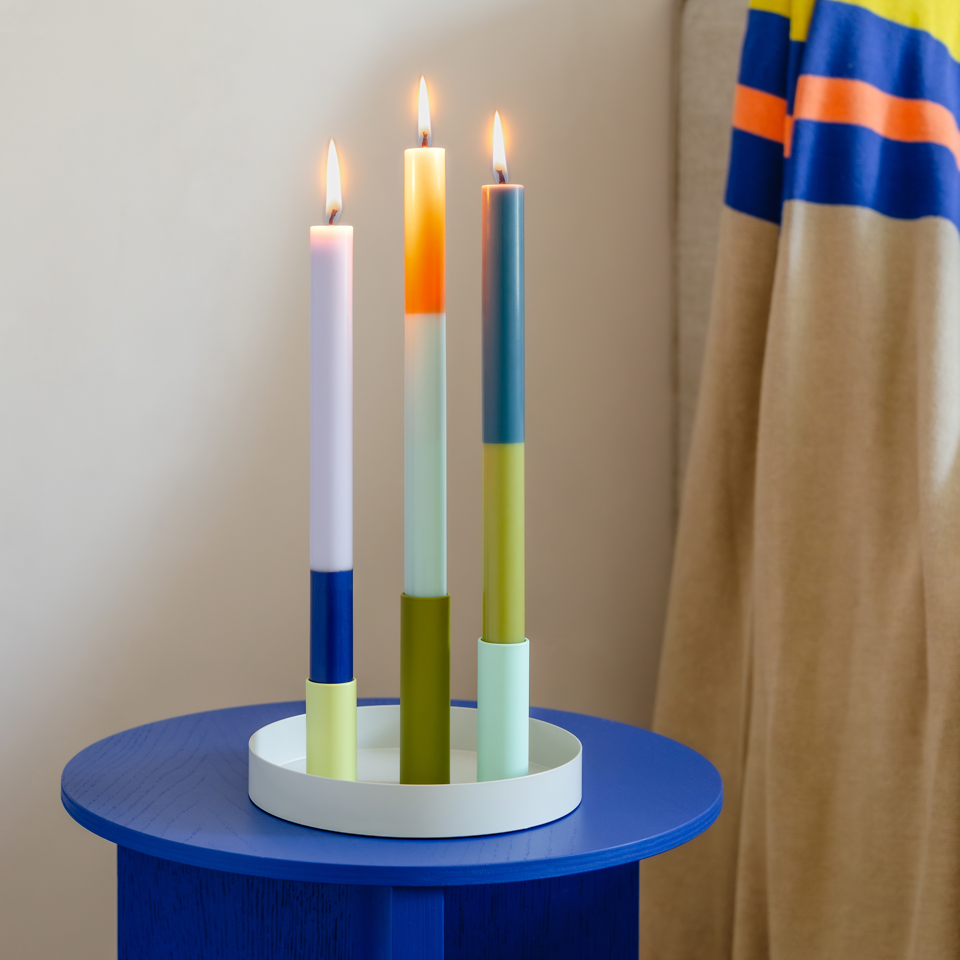 Drei Stabkerzen 'Riga' im Farbblock-Design in Grün/Olive, Orange/Minze und Lila/Dunkelblau, vor weißem Hintergrund.