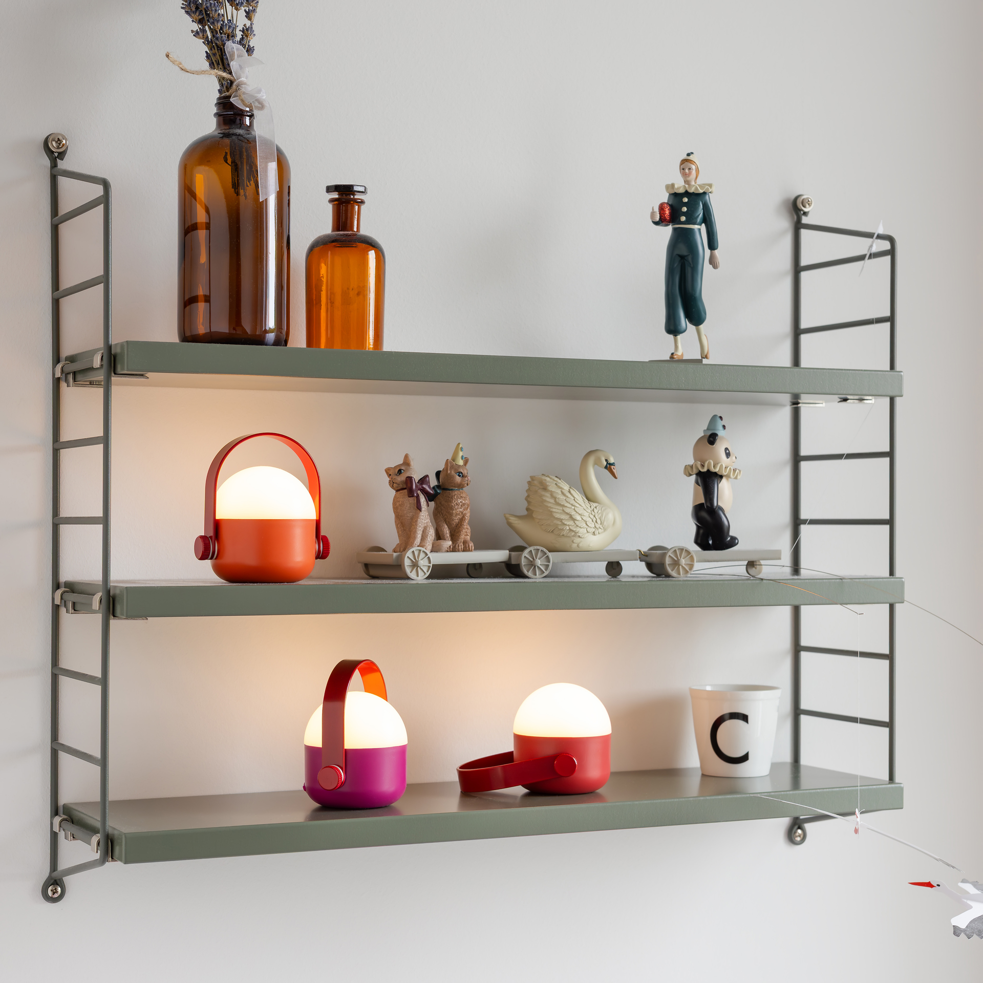 Drei akkubetriebene OLE mini LED-Leuchten nebeneinander: halbkugelförmig, oben weiß leuchtend, Sockel mit rotem Griff; Farben orange-rot, magenta, dunkelrot. Seitlich je ein roter Knopf.