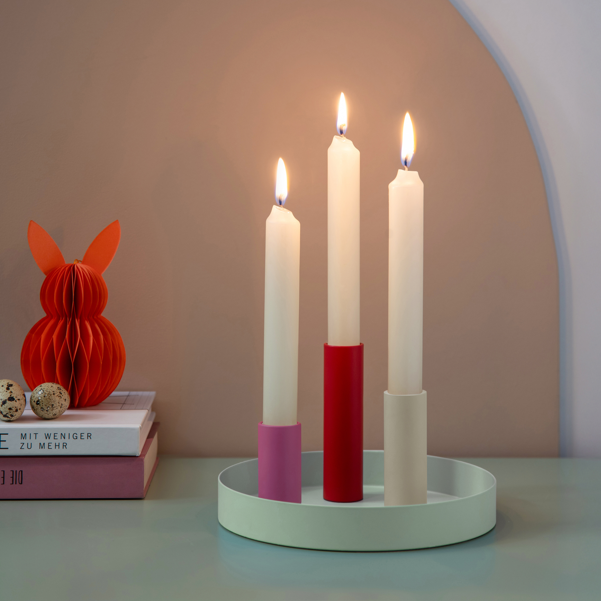 Runder, mintfarbener Magnet-Kerzenhalter 'Luna Mini' mit drei farbigen Haltern (rot, rosa, beige) und zwei beigen Kerzen.