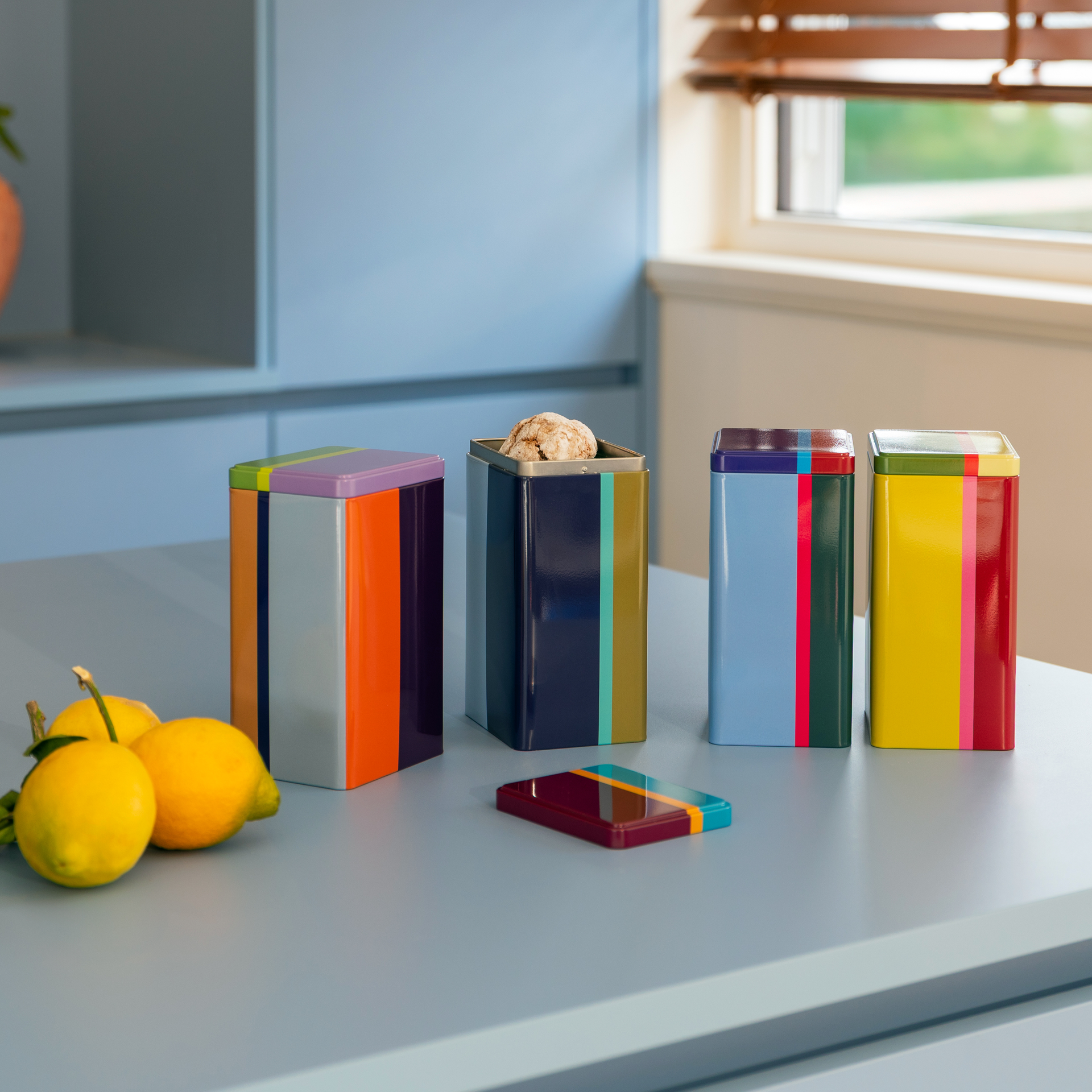 Quatre boîtes 'Yara' rectangulaires et colorées sont alignées. Chaque boîte a son propre motif de couleur avec des rayures et des accents de différentes largeurs.