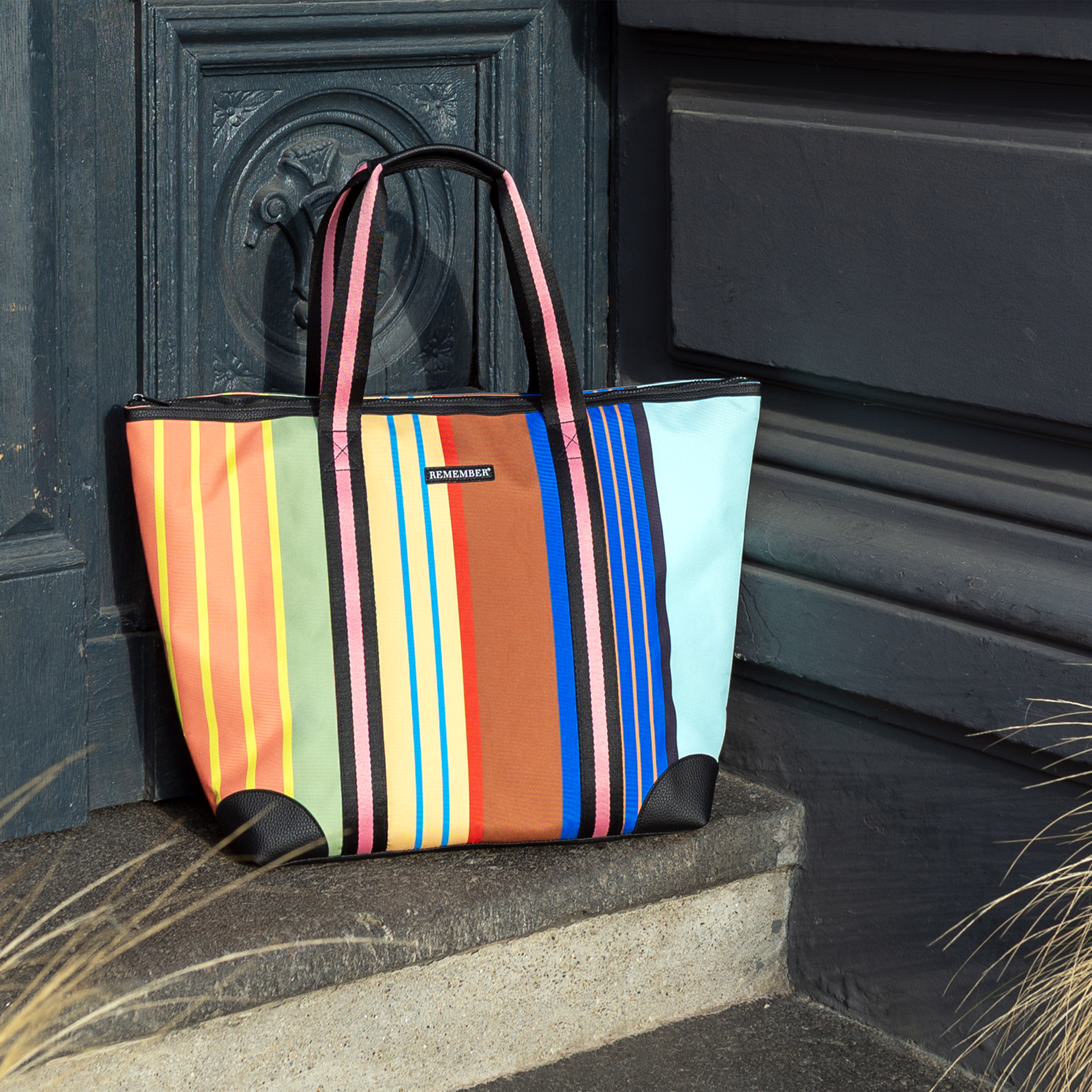 Bunte Shopper 'Barcelona' Tragetasche mit Streifenmuster und schwarzen Tragegriffen, Lederimitat am Boden.