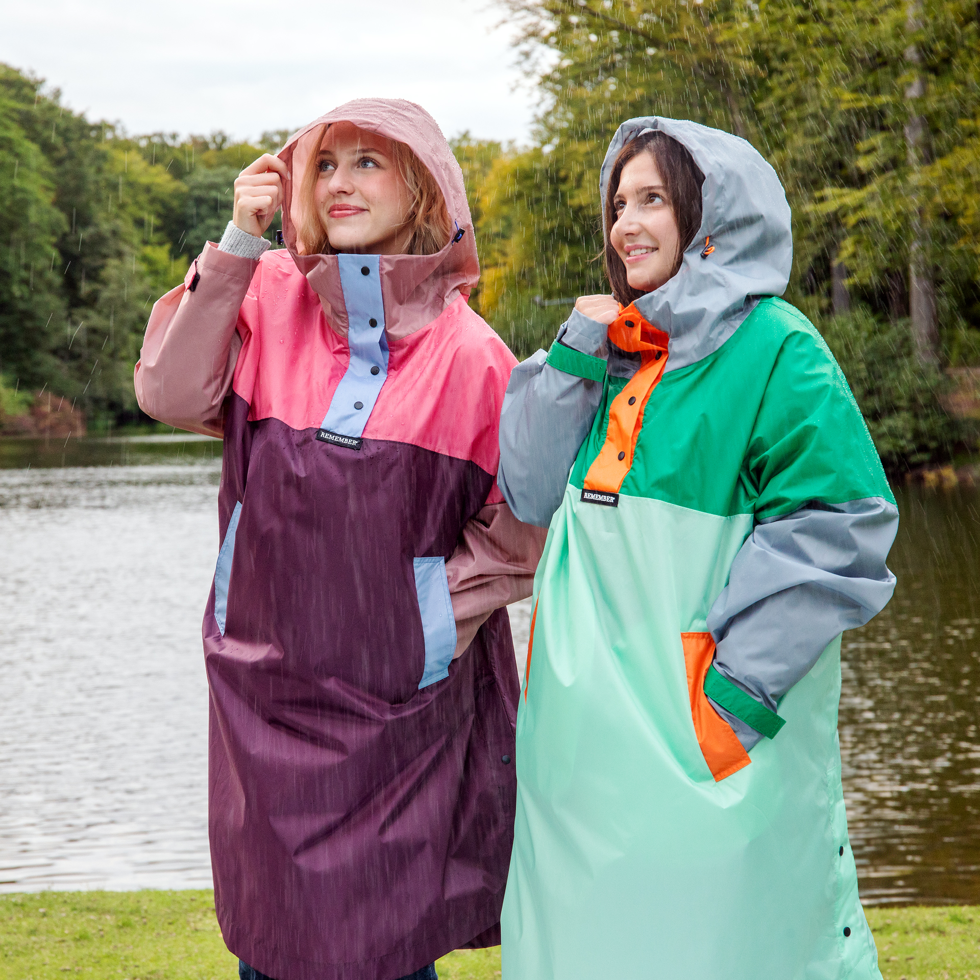 Zwei Frauen tragen die Regen-Capes der Marke Ida im Regen. Die Capes sind farbenfroh, verfügen über Kapuzen und Taschen und bieten Schutz vor Nässe.