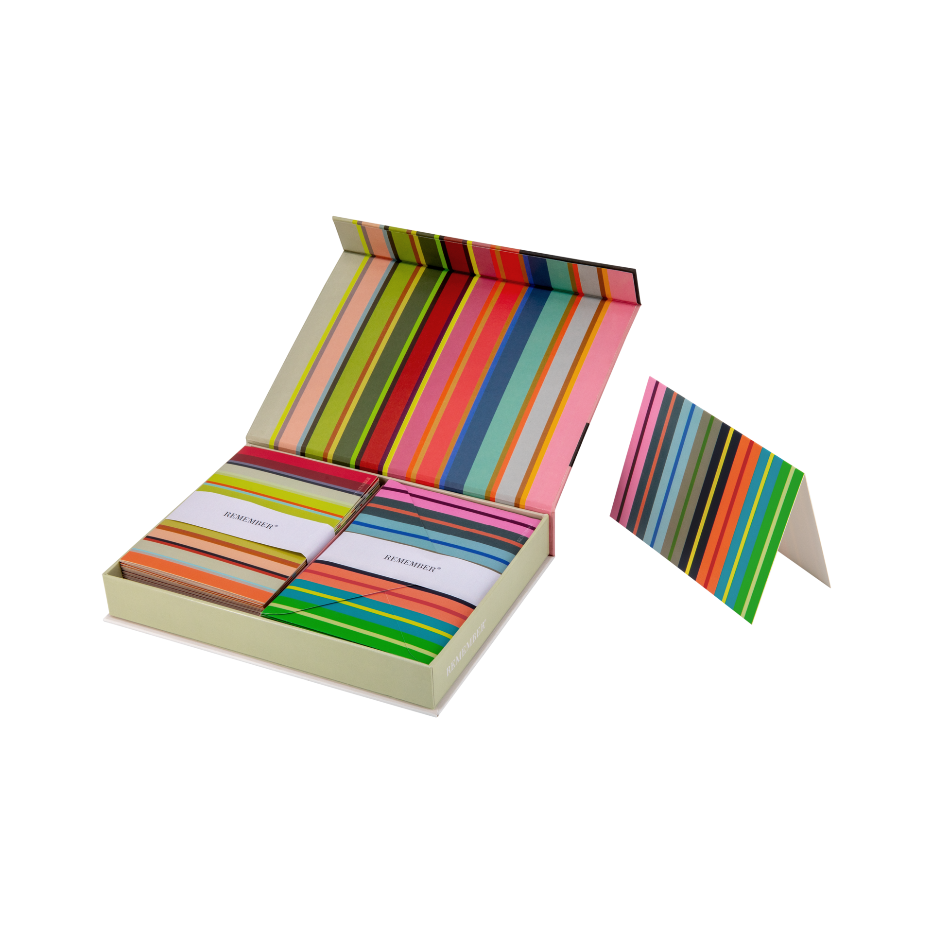 Boîte magnétique ouverte avec piles de cartes pliables rayées et enveloppes assorties. Chaque pile est entourée d’un ruban blanc «REMEMBER ». À droite, une carte dépliée au même motif à rayures.