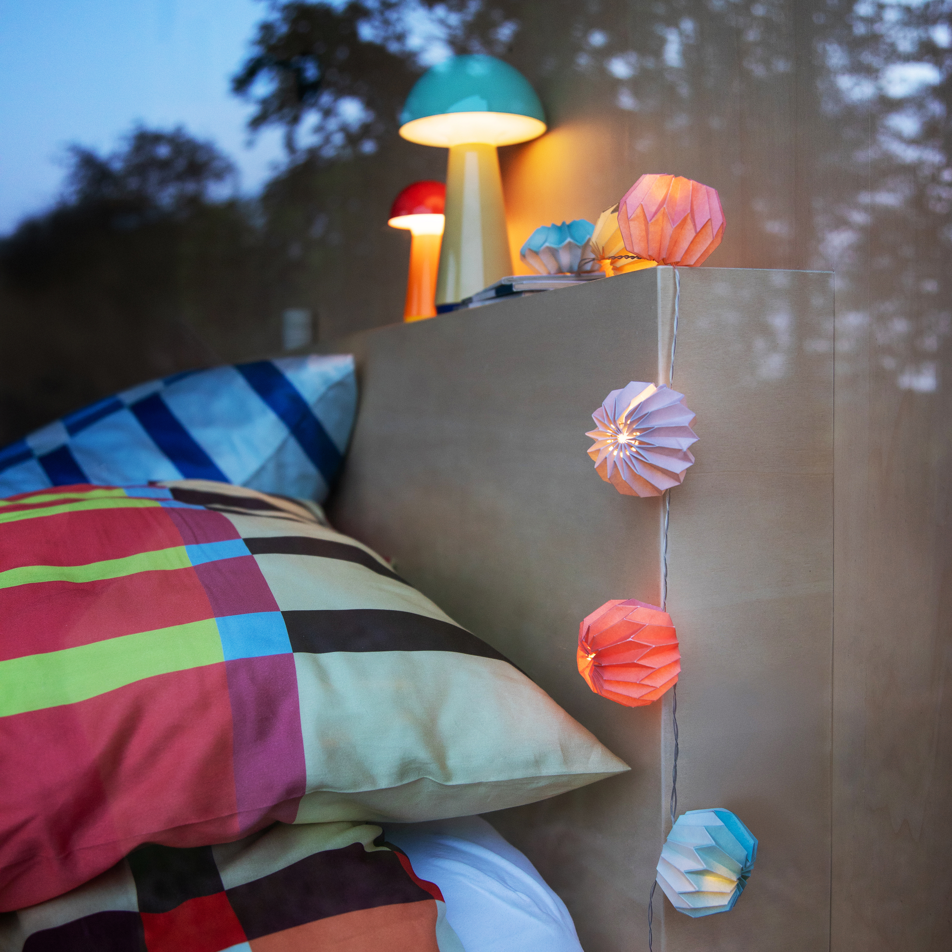 Eine Papier-Lichterkette Yazz mit zehn bunten, gefalteten Papierkugeln an einem weißen Kabel. Ein transparentes Batteriefach ist am Ende befestigt.