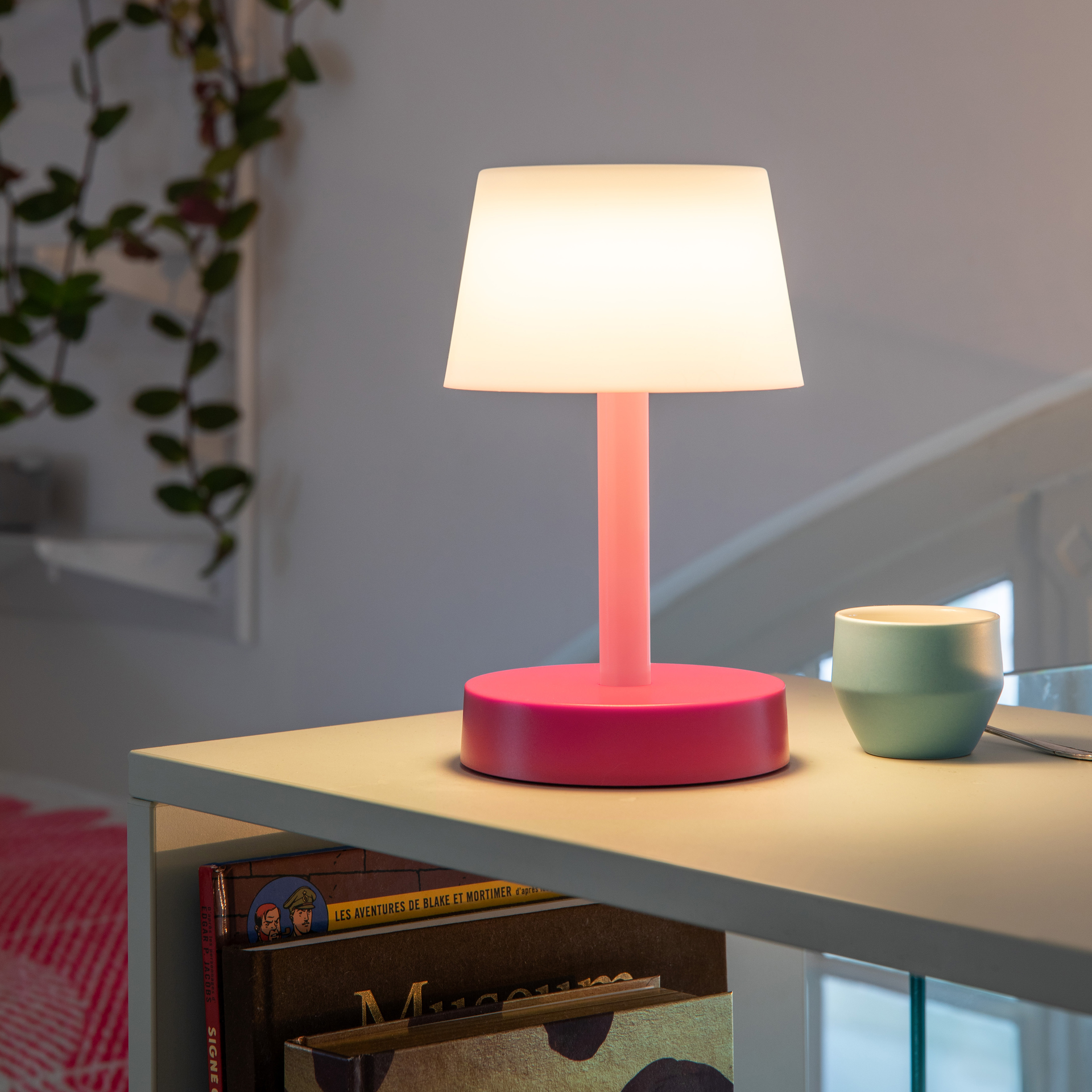 Lampe de table indépendante 'Fritz' en corail. La lampe a un abat-jour blanc, une tige de couleur corail et un pied rond de couleur corail.