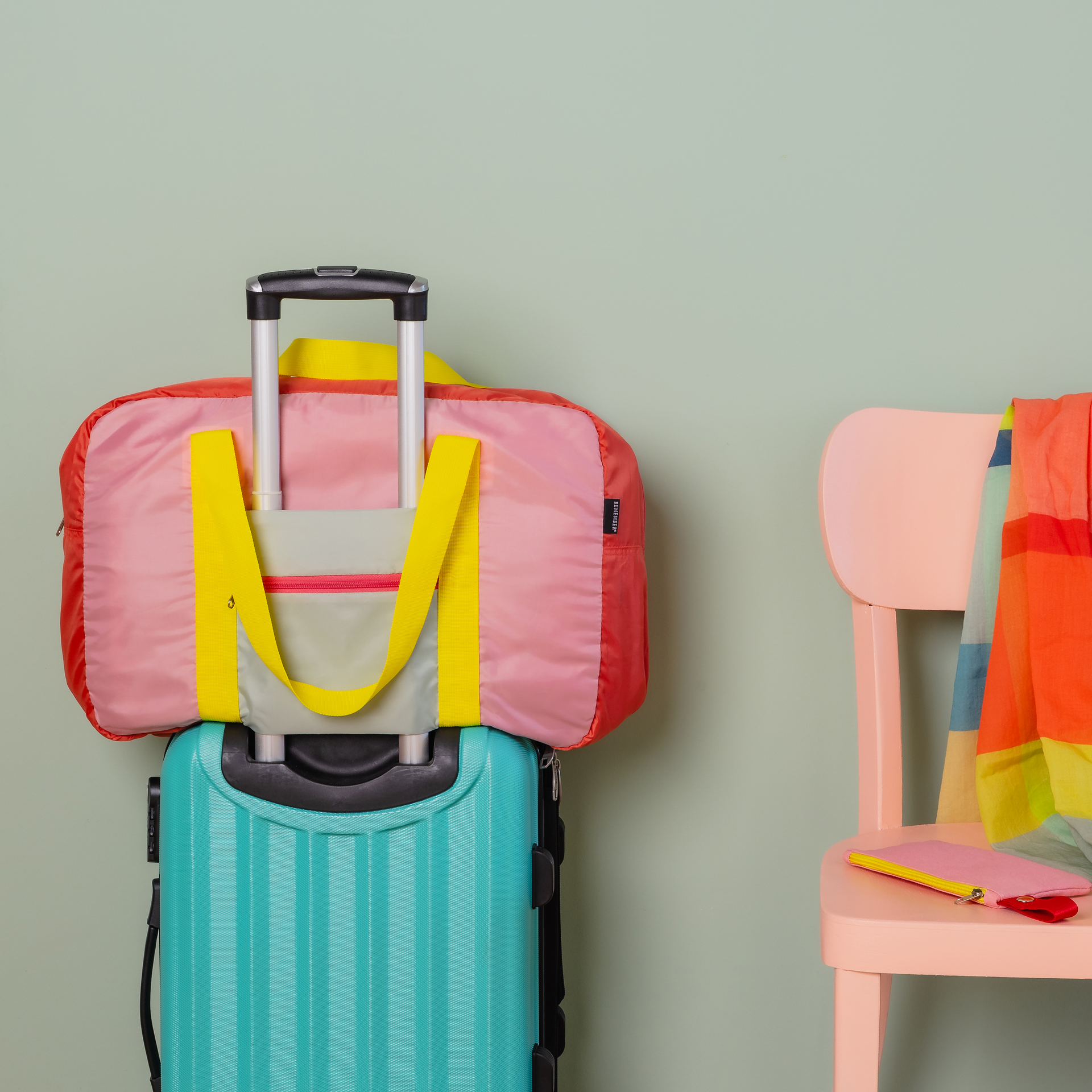 Rechteckige Reisetasche 'Rosi' in Rot, Rosa und Grün mit gelben Tragegurten und Reißverschlüssen vor hellem Hintergrund.