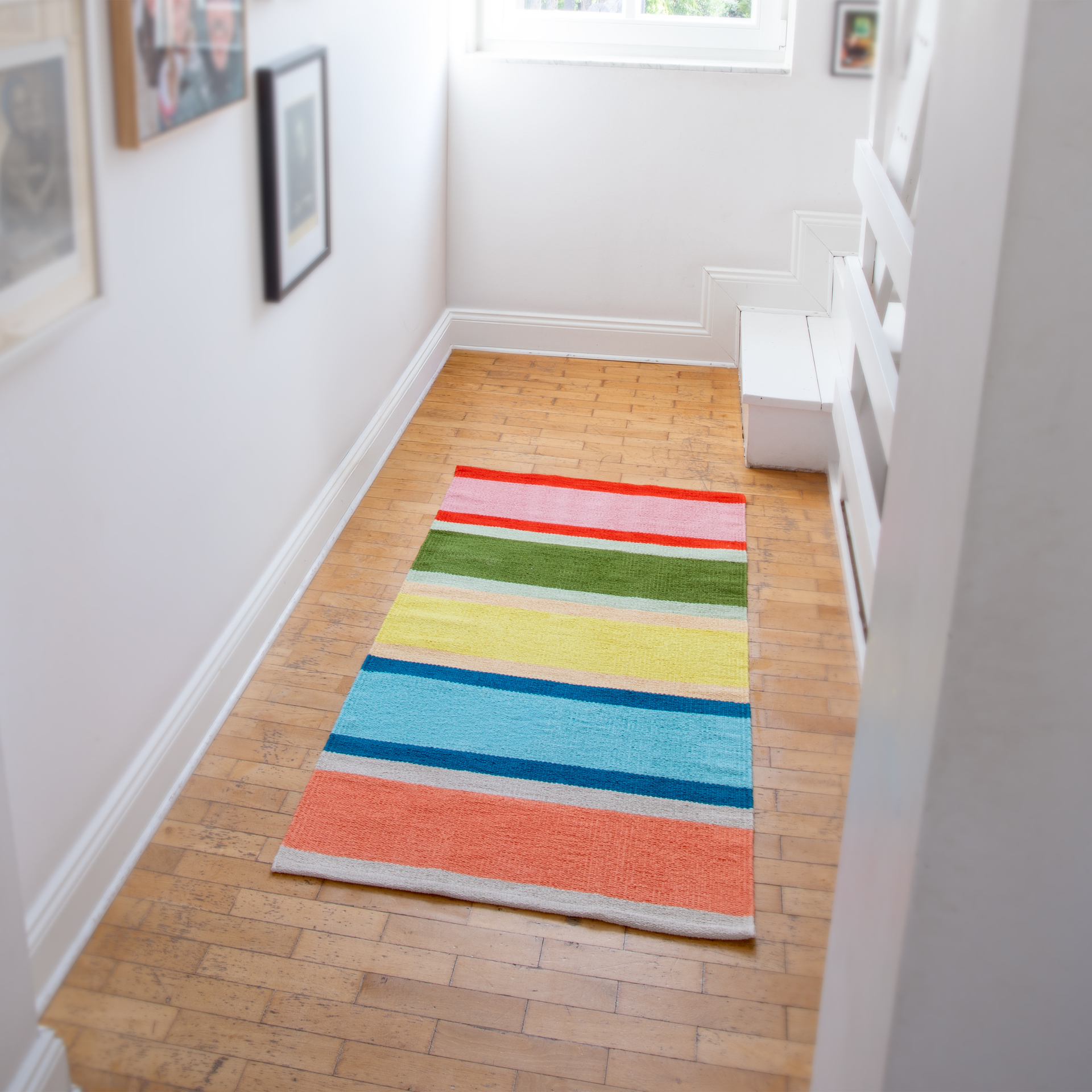 Tappeto a strisce colorate con strisce verticali nei toni del rosso intenso, rosa tenue, verde oliva, giallo brillante, turchese, azzurro e arancione corallo, separate da sottili strisce color crema. Pile corto per un tocco di allegria.