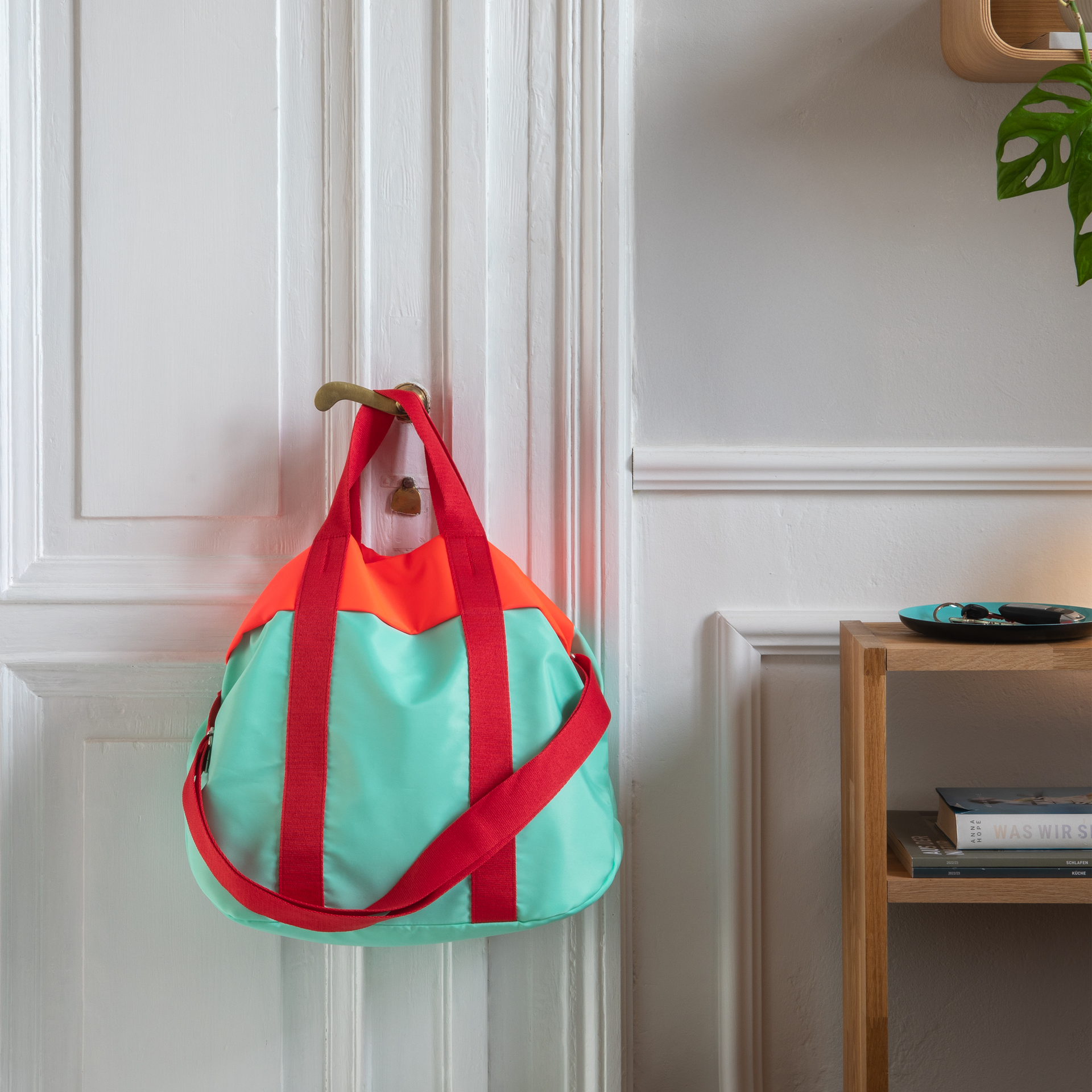 Turquoise cabas 'Nelly' avec bretelles rouges et bord supérieur en corail sur fond blanc.