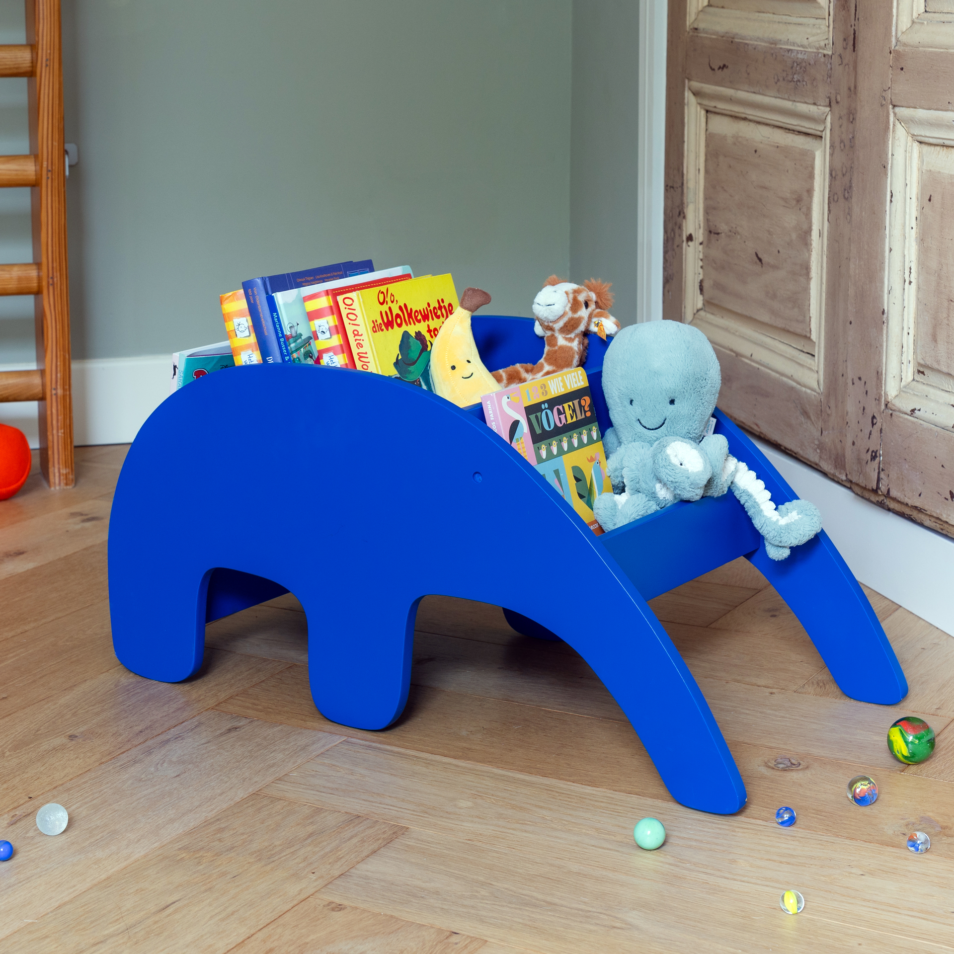 Blaues Bücherregal im Design eines Ameisenbärs mit Fächern. Das Regal steht auf vier Beinen, die den Körper des Tieres darstellen. Der Kopf ist abgerundet, ein kleines Loch ist als Auge zu erkennen.