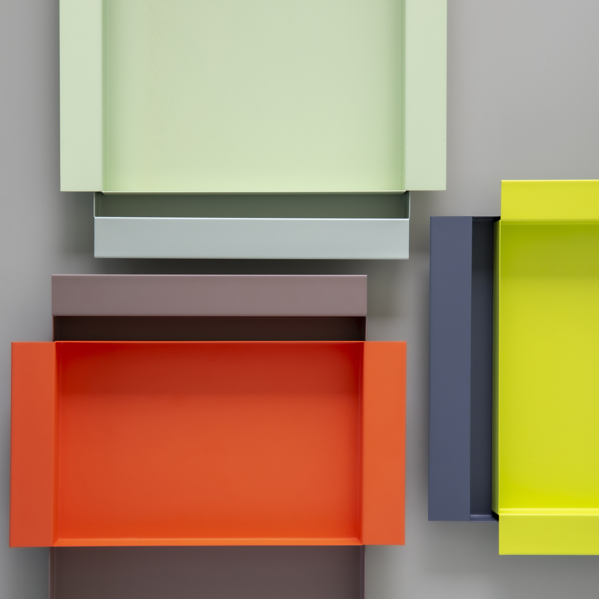 Detailansicht mehrerer farbiger Metall-Tabletts. Farben: Mint, Lime, Aquamarin, Mocca, Koralle, Mitternachtsblau. Die Tabletts sind teilweise ineinandergesteckt.