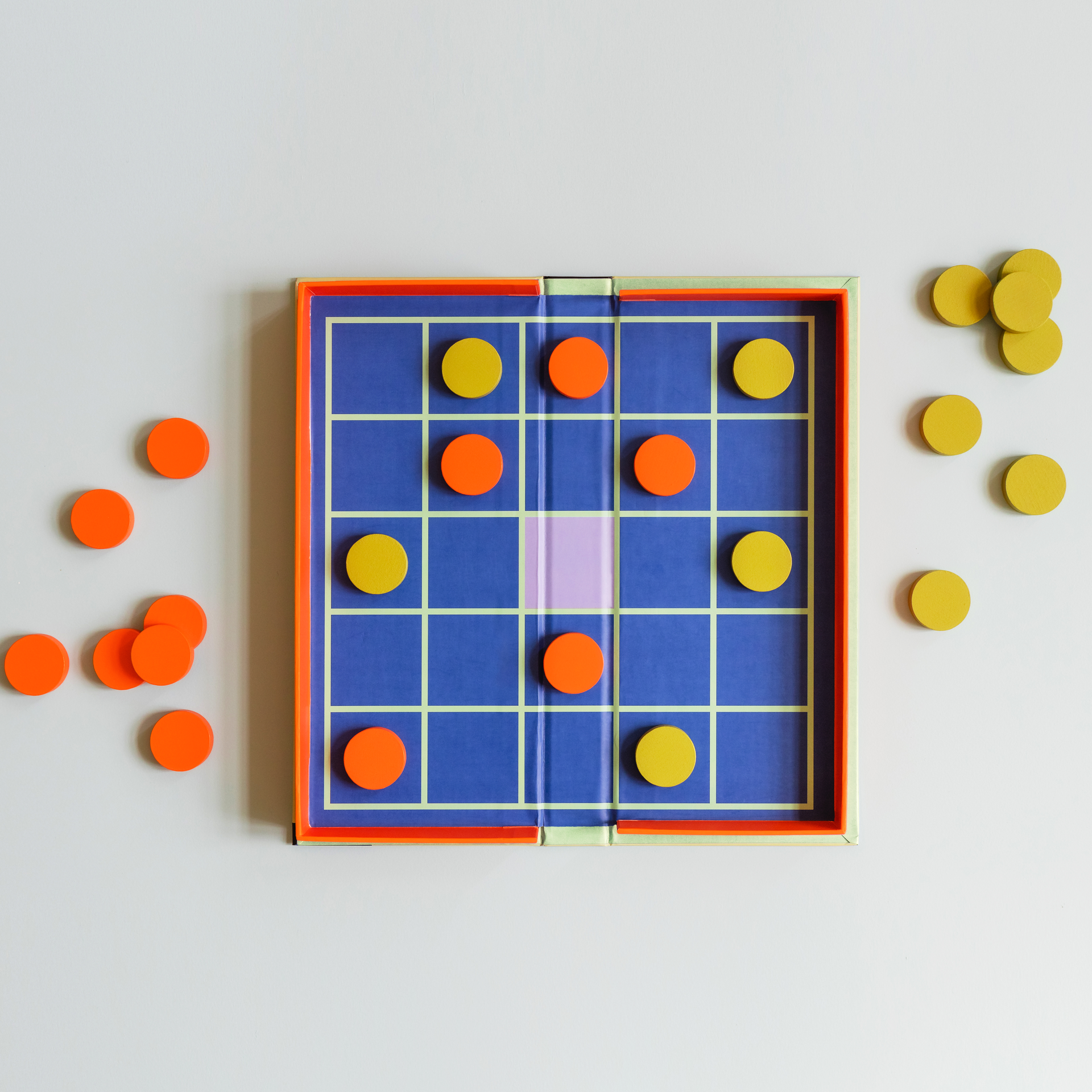 Seega Spielbrett mit gelben und orangenen Spielsteinen.