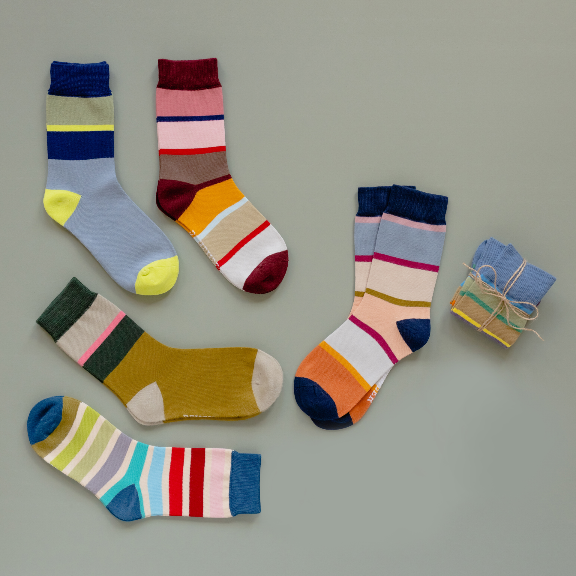 Zwei gestreifte Socken in blau, grau und gelb, übereinander liegend.