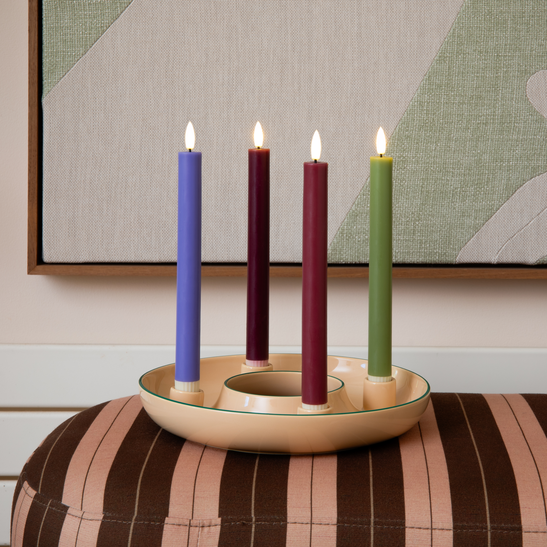 Coupelle à bougies ronde « Lucia » beige, en céramique dolomitique, avec 4 supports pour bougies cylindriques. 4 bougies bicolores : vert menthe-rouge, vert menthe-rouge foncé, orange-bleu, vert olive-vert citron vert. Décoration chaleureuse.