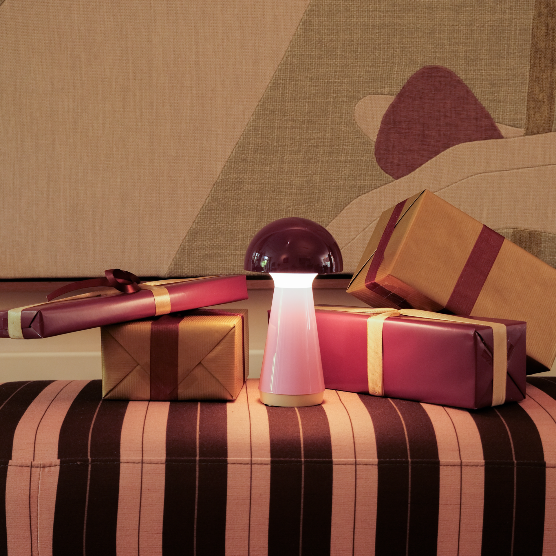 Lampada da tavolo compatta a forma di fungo su sfondo bianco. Testa luminosa lucida rosso bacca, collo corto bianco. Corpo conico rosa chiaro con bordo beige in basso. LED senza cavo, dimmerabile, resistente agli spruzzi.