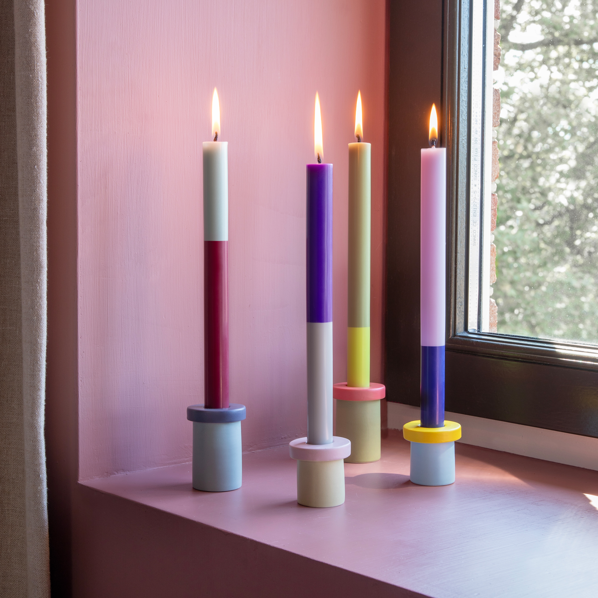 Drei 'Oslo' Stabkerzen im Color-Blocking-Design. Die erste Kerze ist zweifarbig, oben mintgrün und unten weinrot. Die zweite Kerze ist oben olivgrün und unten gelb. Die dritte Kerze ist oben lila und unten hellgrau.