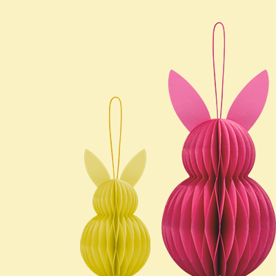 Zwei Papierhasen, gelb und pink, als Dekoration mit Aufhänger. Die Körper sind wie eine Ziehharmonika gefaltet.