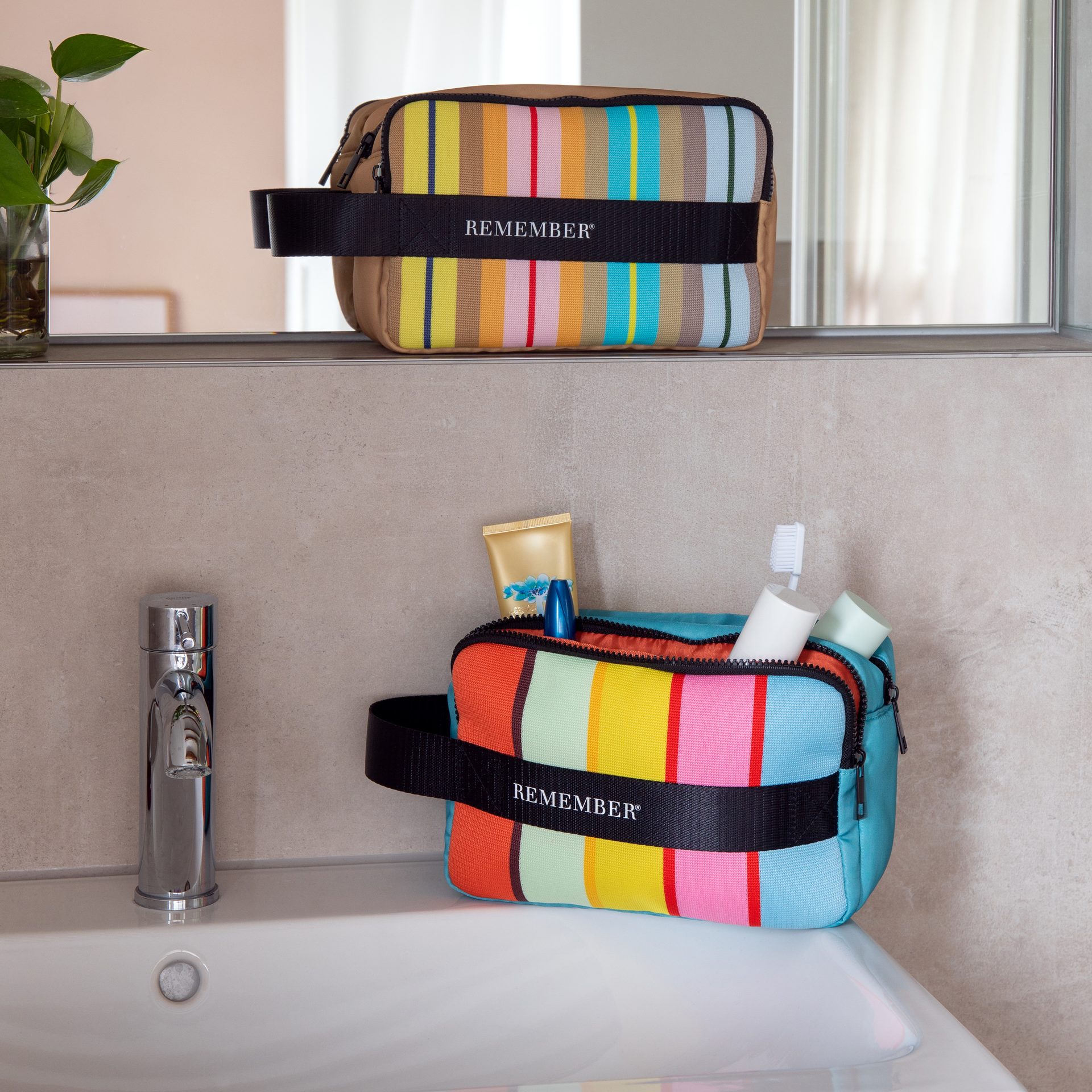 Trousse de toilette Ventara beige, avec motif à rayures verticales colorées (jaune, bleu, orange, rose, vert) sur l’avant. Bande noire «REMEMBER® » autour, faisant poignée. Compartiment principal zippé noir.