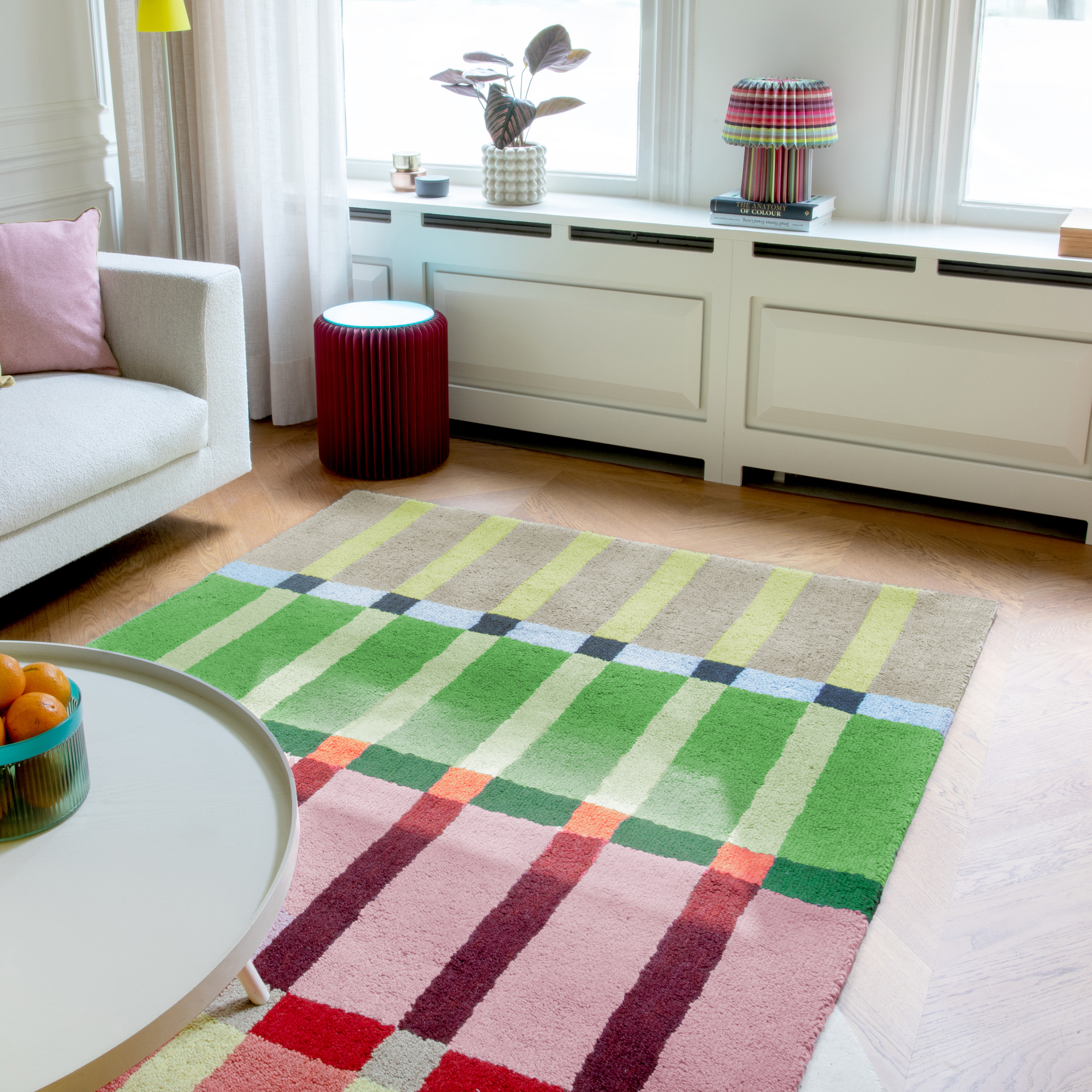Tappeto rettangolare 'Kaido' con un motivo a strisce colorate in beige, verde, rosa e rosso. Le strisce sono disposte orizzontalmente. Accenti di colore verticali collegano le aree colorate.