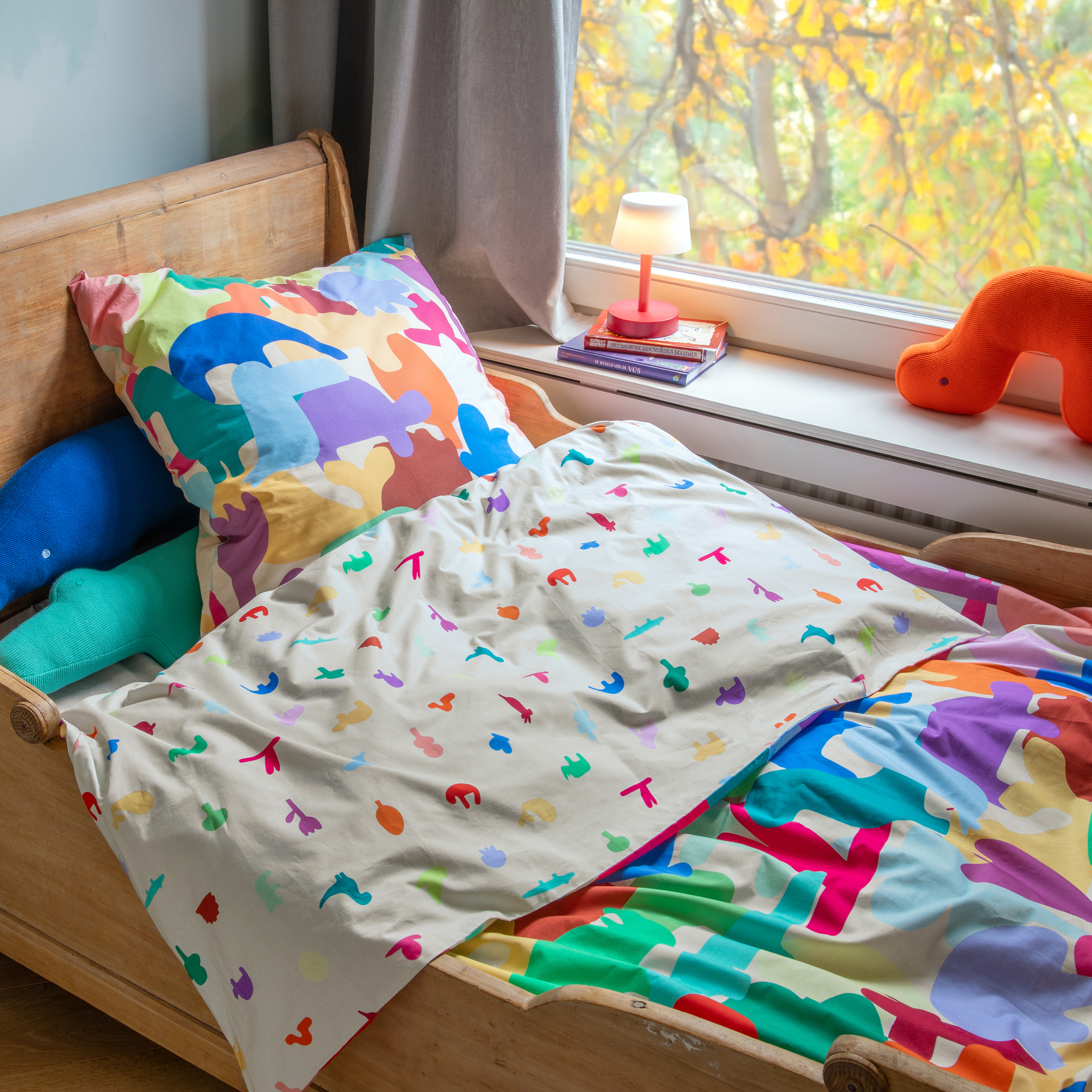 Kinderbettwäsche Animals mit Kissen und Decke, die mit bunten Tierformen und Blumen auf hellem Hintergrund bedruckt sind.