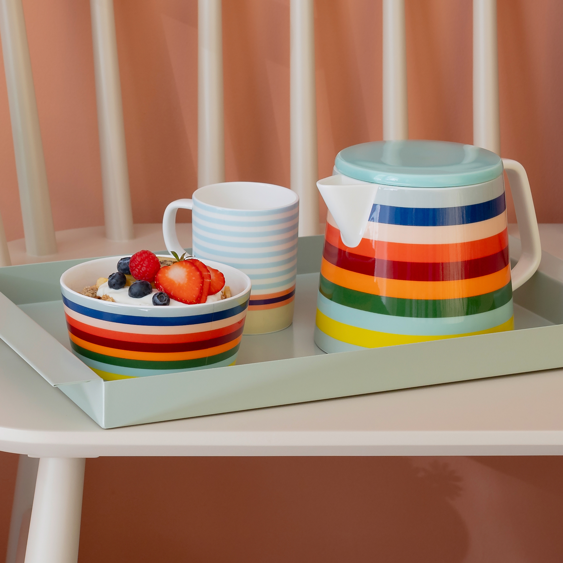 Eine Teekanne 'Lorenzo' mit bunten Streifen, eine Tasse mit hellblauen Streifen und eine Schale mit Joghurt und frischen Früchten auf einem mintgrünen Tablett.