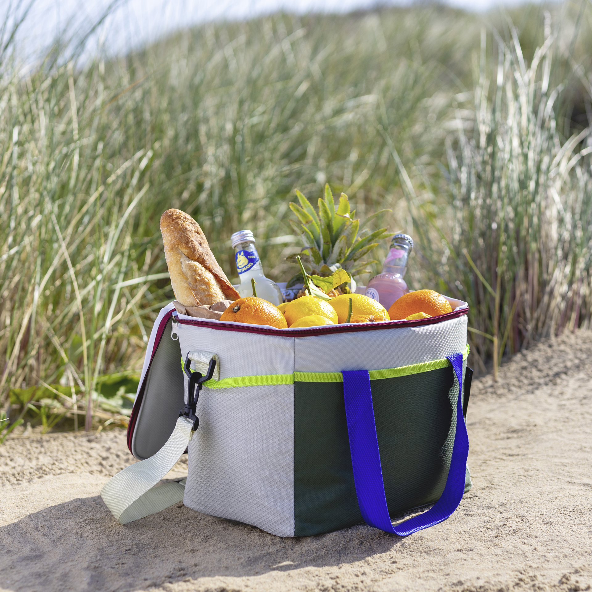 Freistehende, rechteckige Kühltasche 'Bruno' mit Tragegriffen, Schultergurt und Reißverschluss. Farblich in Beige, Grün und mit blauen Akzenten.
