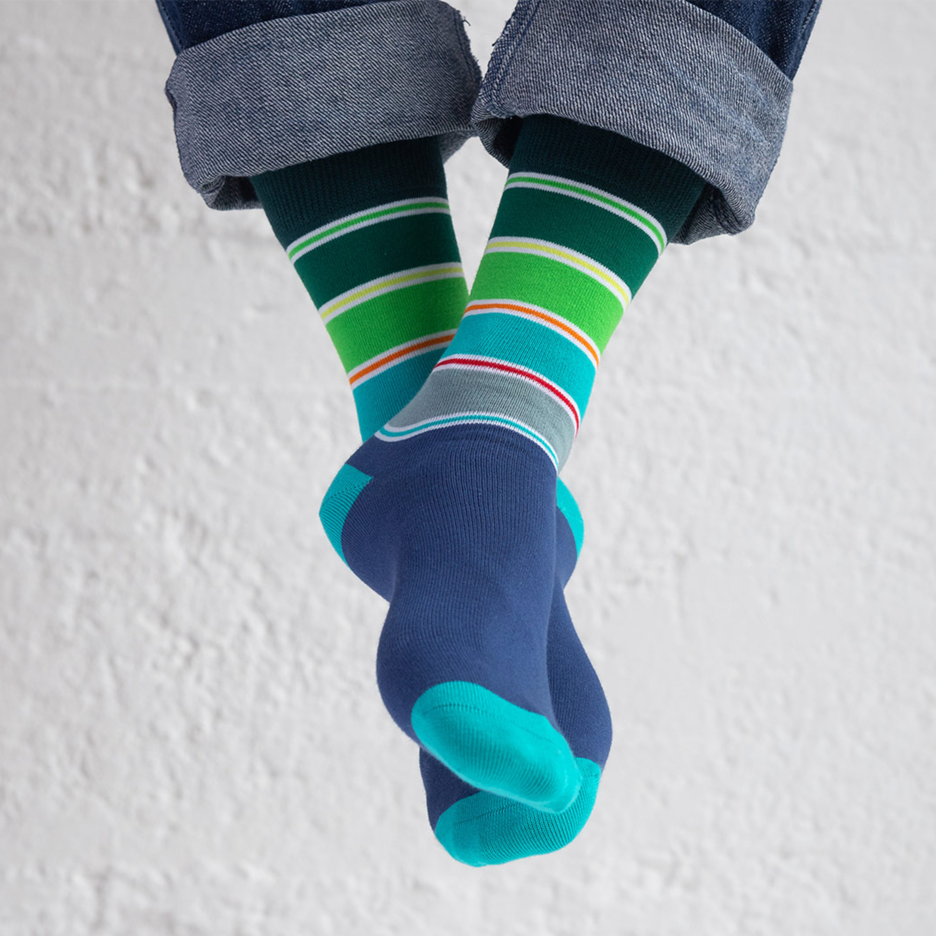 Zwei Socken der Größe 41-46 mit blauem Fußteil und türkisem Zehenbereich. Das Bündchen ist dunkelgrün mit farbigen Streifen in grün, gelb, rot und grau.