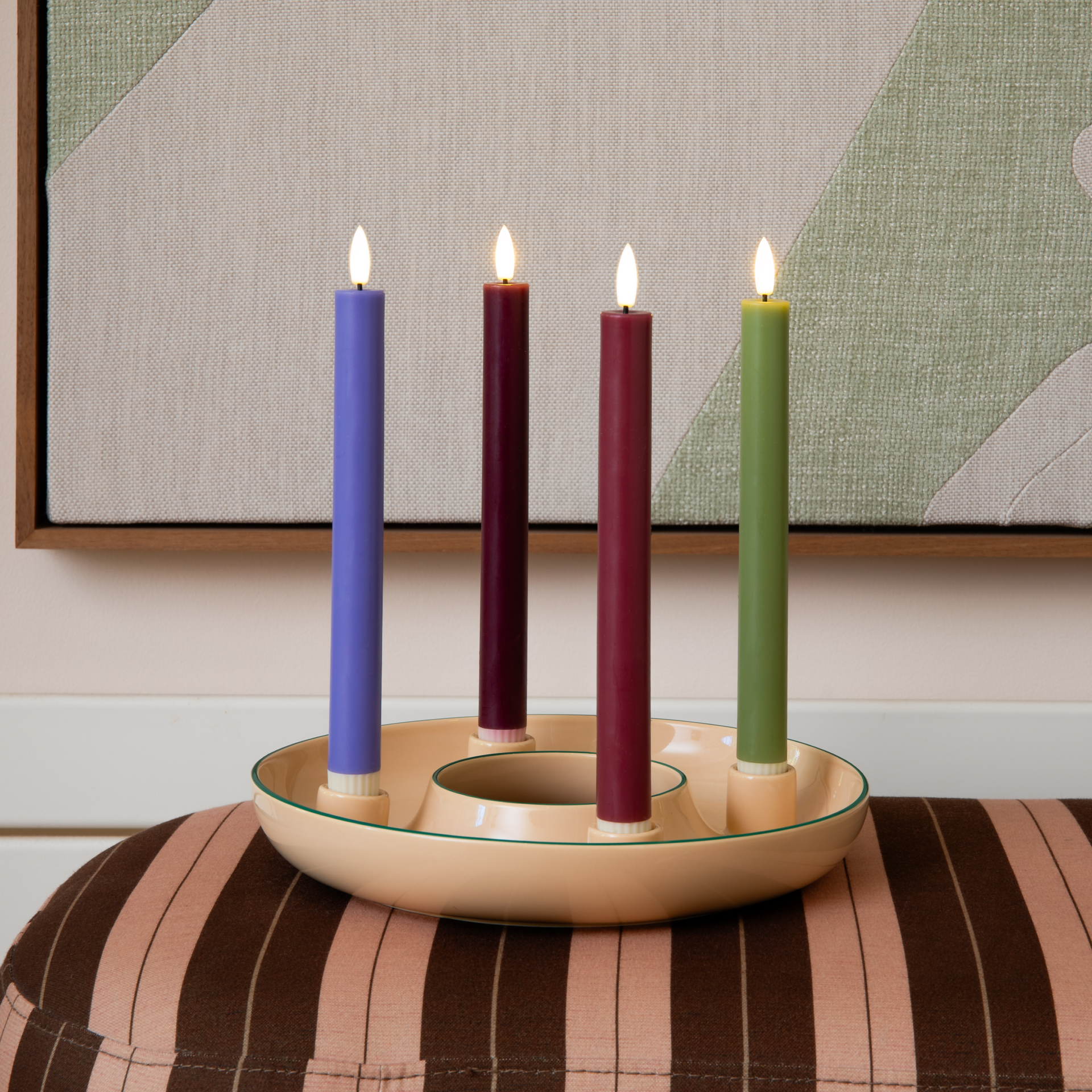 Due candele a bastoncino a LED (rosso bordeaux e color lavanda) su sfondo bianco, con stoppino bianco a forma di fiamma e base bianca scanalata. Accanto, un telecomando bianco con pulsanti. Altezza: 24,5 cm.