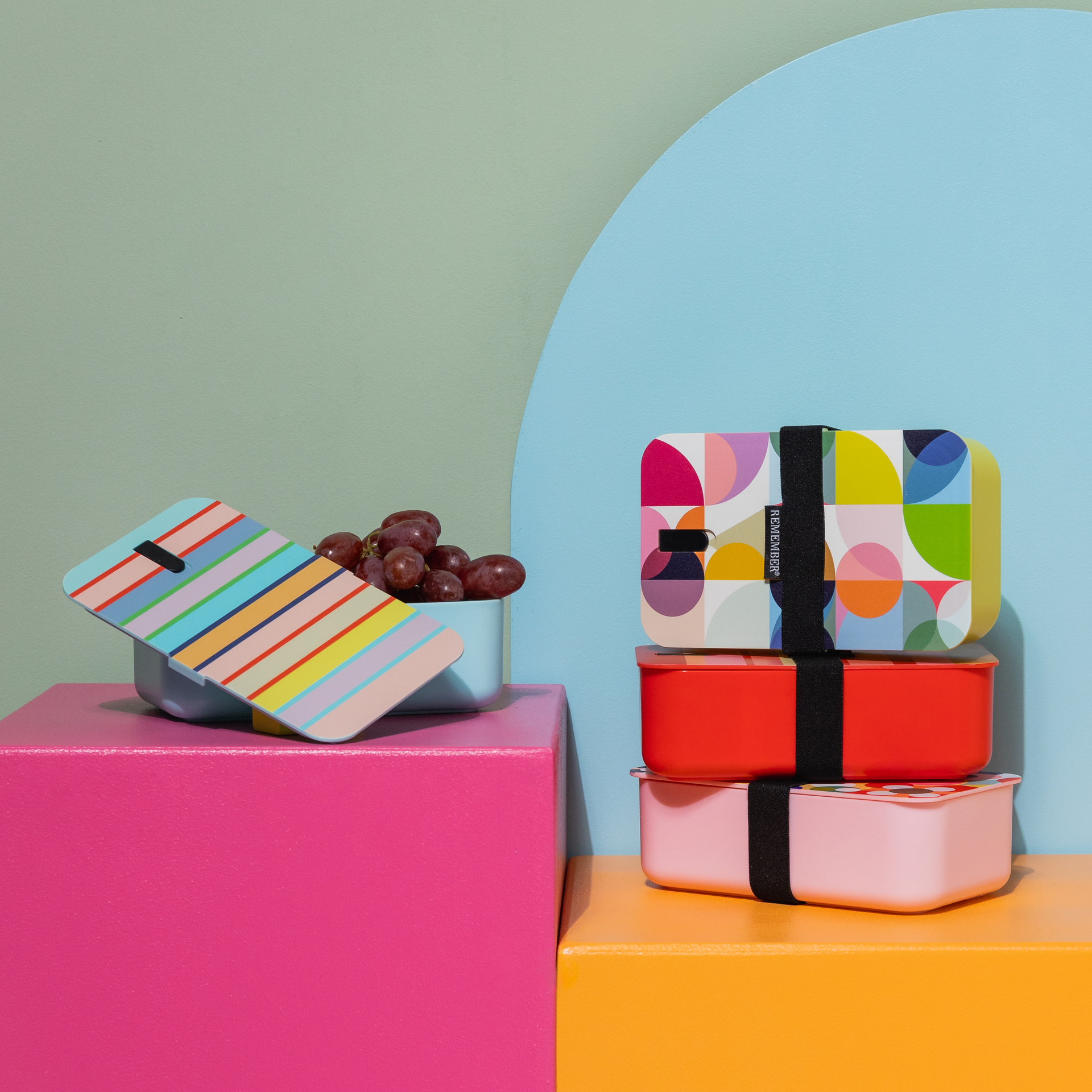 Rosa Lunchbox 'Remember 30' mit farbenfrohem, floralem Deckel und schwarzem Gummiband. Links ist eine blaue Sprechblase mit der Zahl 30 zu sehen.