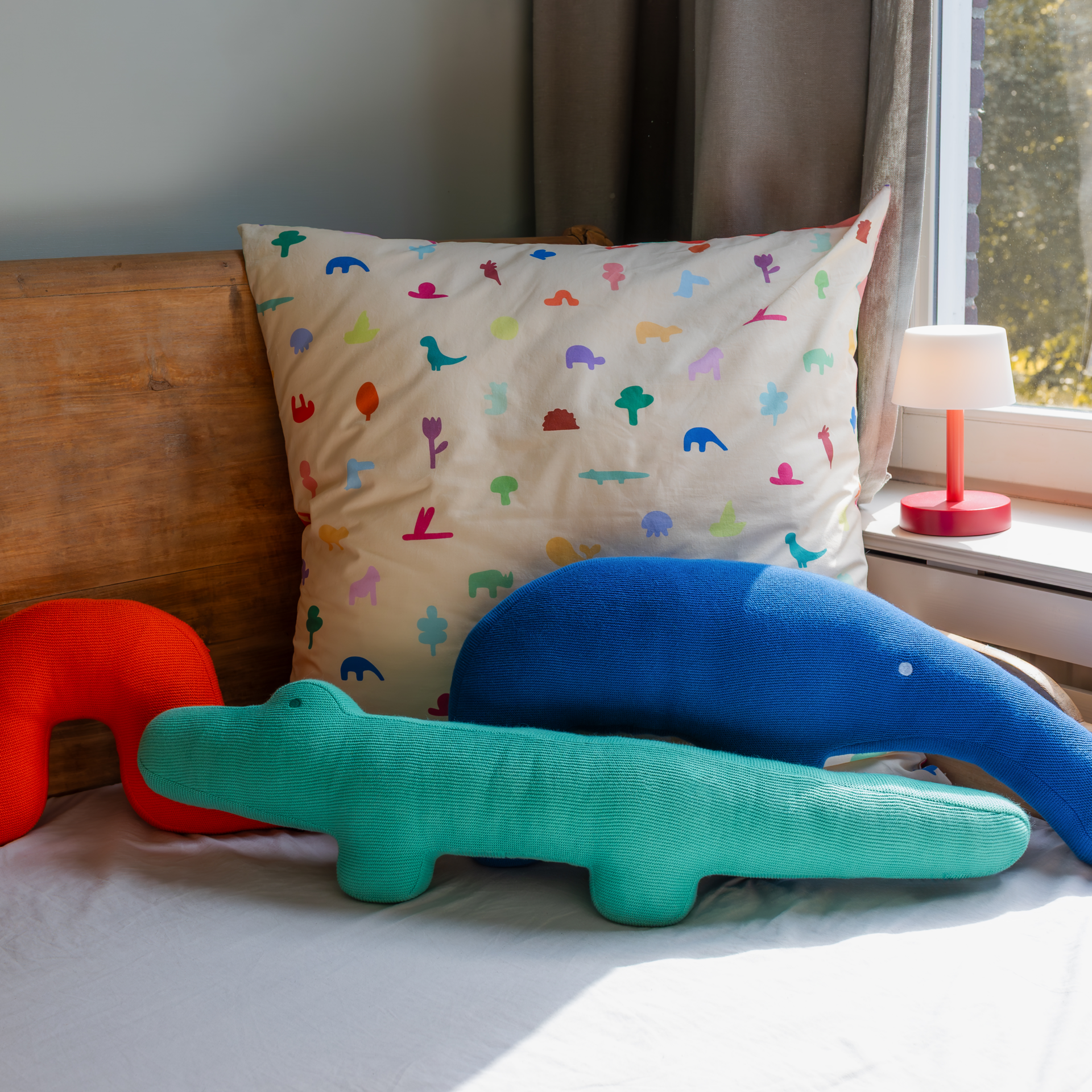 Türkisgrünes Kuschelkissen in Form eines Krokodils, 'Kroko Karl', mit kleinem Auge und vier kurzen Beinen vor einem weißen Hintergrund.