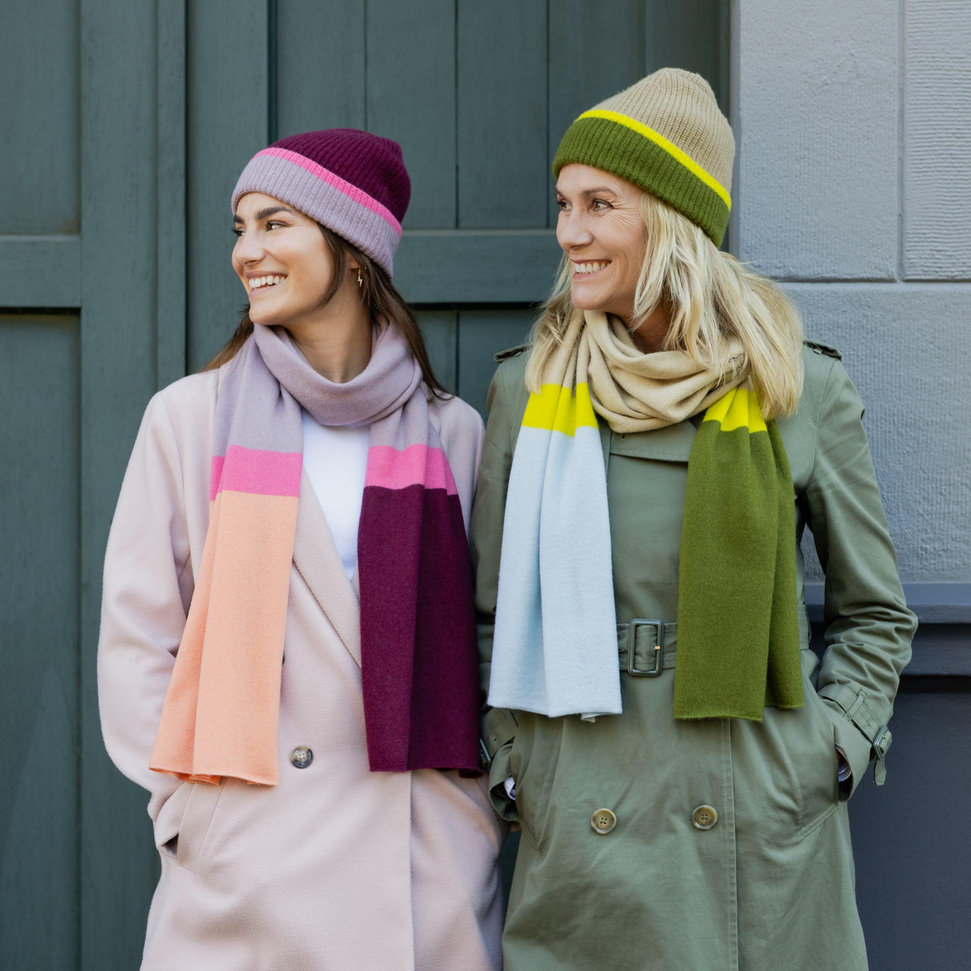 Ein Woll-Kaschmir-Schal in Rosa- und Orangetönen, mit einem Farbakzent in Pink und Dunkelrot. Der Schal ist locker drapiert und hängt auf einem weißen Hintergrund.