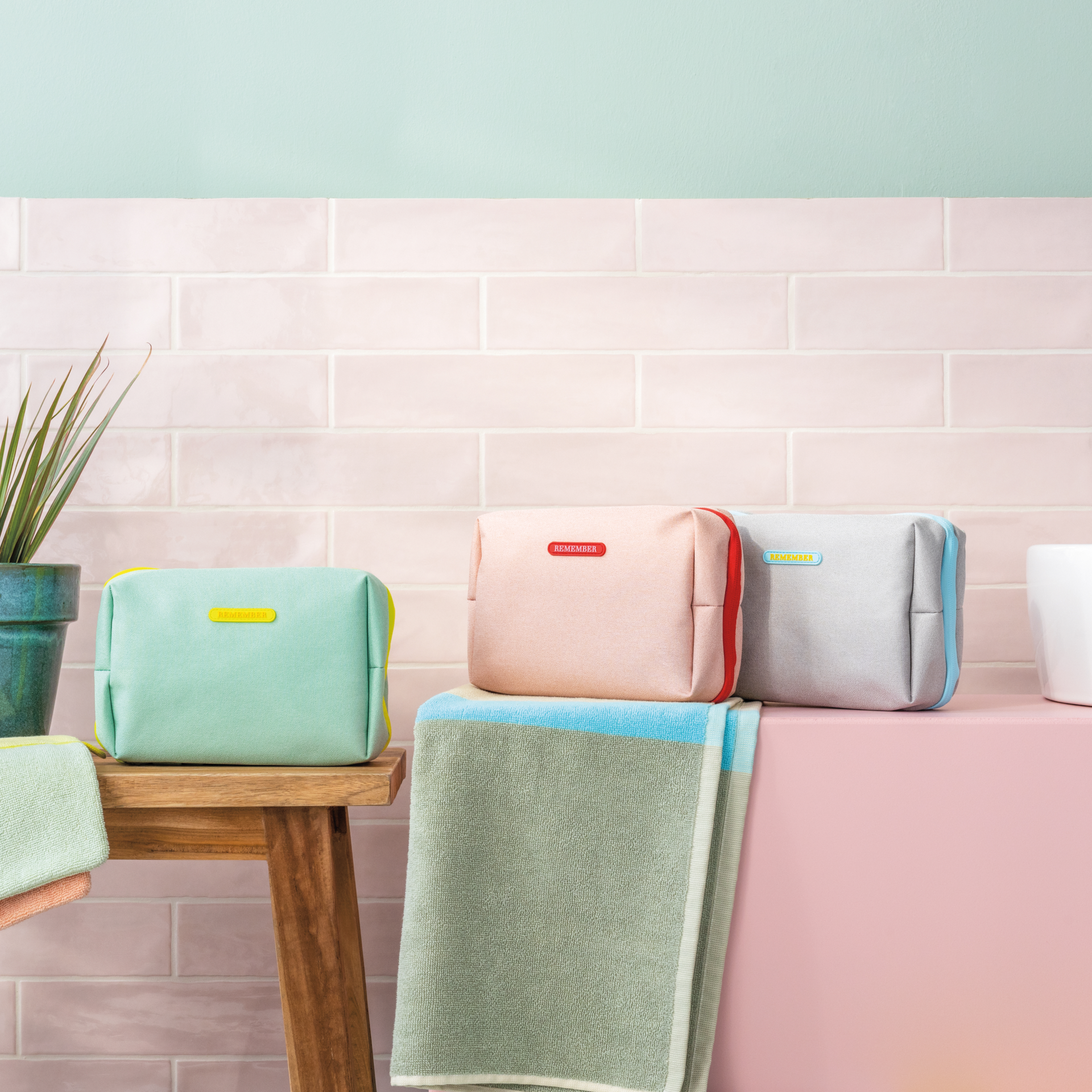Beige Kulturtasche 'Ocean' mit hellblauem Reißverschluss und Anhänger. Ein 'REMEMBER'-Logo ist mittig auf der Tasche platziert.