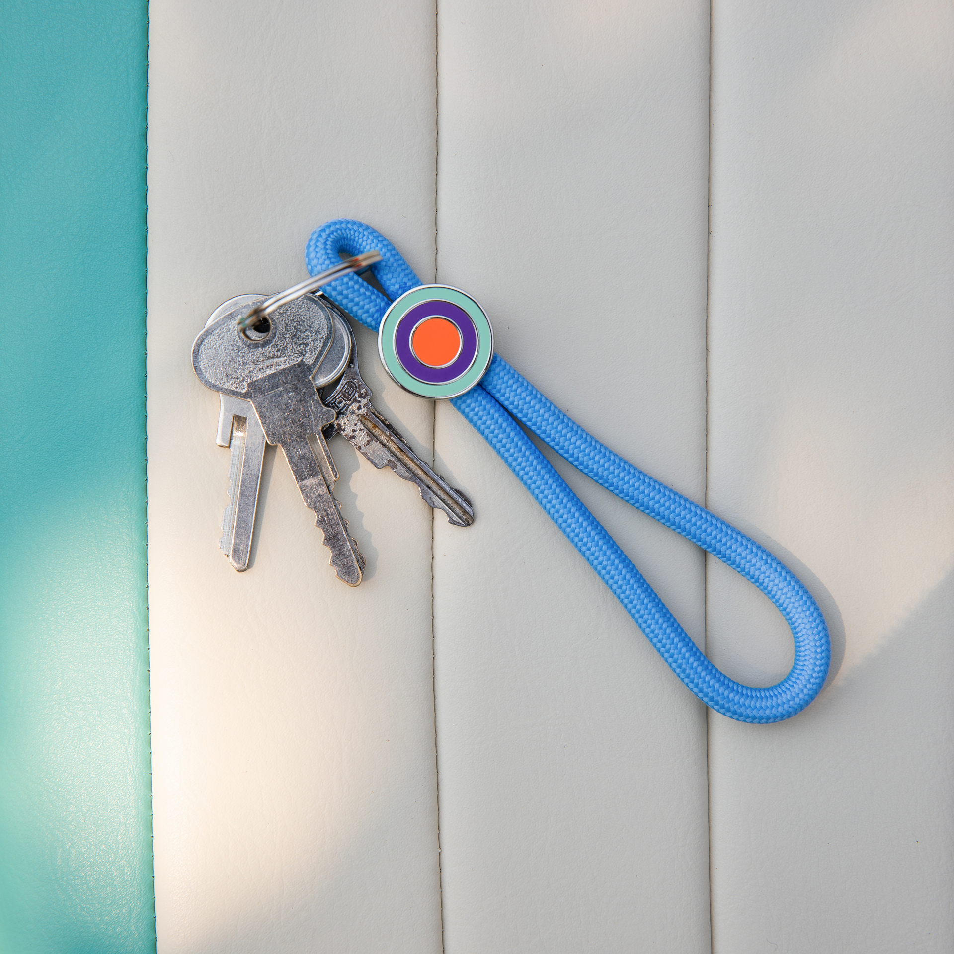 Schlüsselanhänger Ringo blue: Zwei Schlüssel an blauem Anhänger mit Kreisen in Orange, Lila und Mint auf hellem Untergrund.