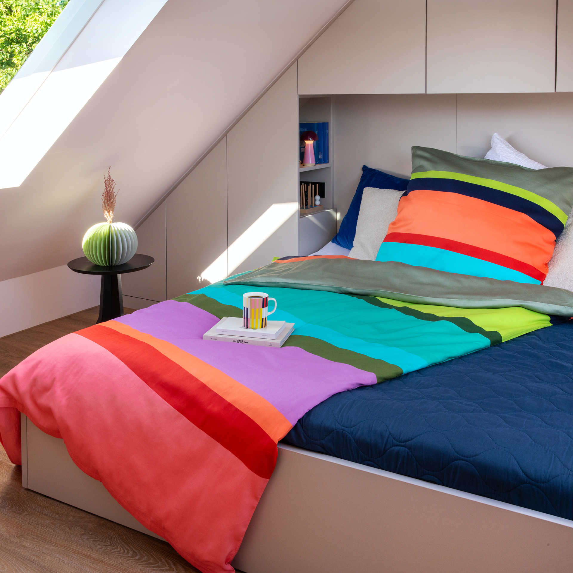 Parure de lit plissée en satin Mako très doux, avec taie d'oreiller et housse de couette. Les deux housses présentent de larges rayures horizontales aux couleurs vives : beige, jaune, bleu foncé, corail, rouge, etc.