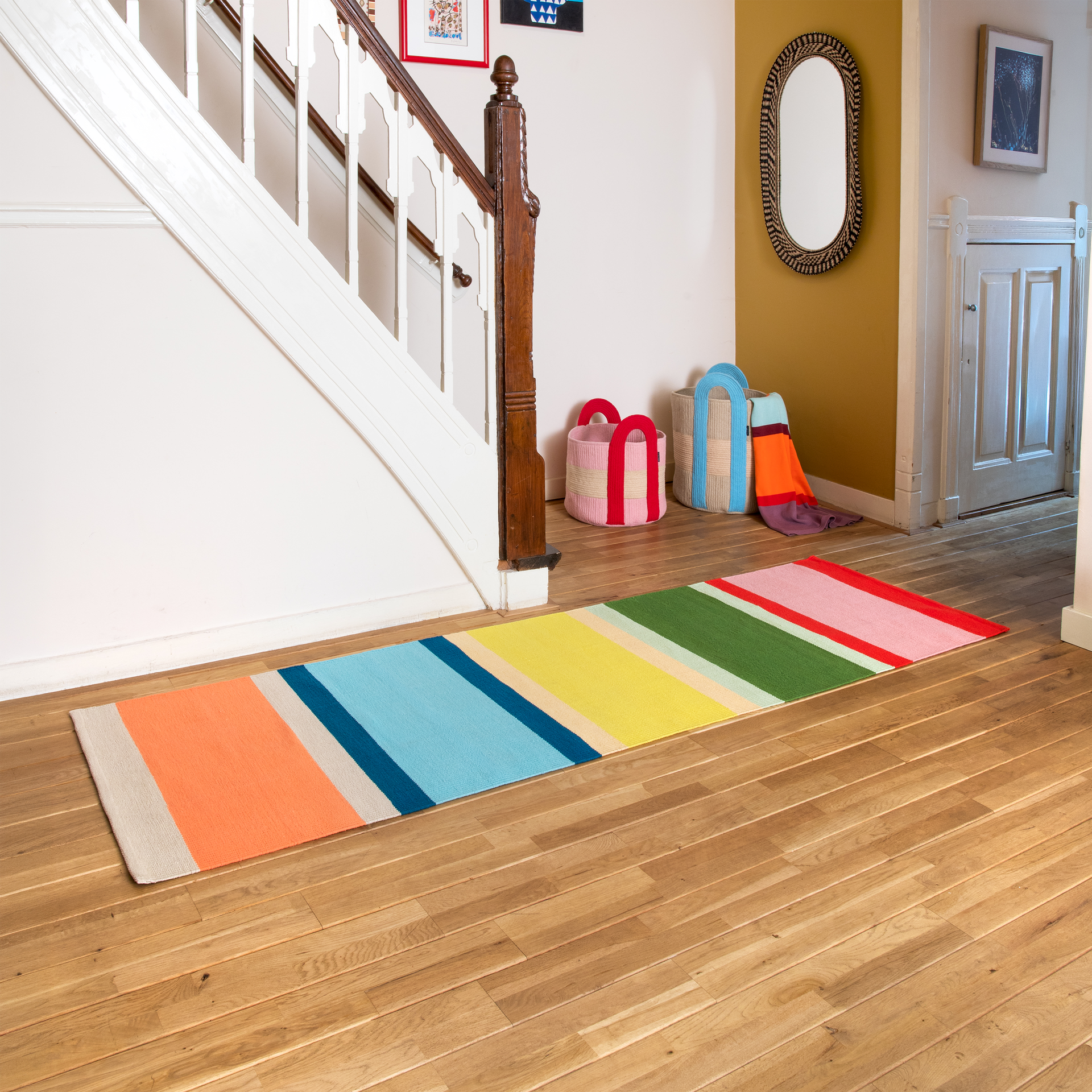 Long tapis de passage tissé à la main, orné d'un motif à rayures colorées. Larges rayures verticales roses, vertes, jaunes, bleu clair et orange, rehaussées de fines lignes rouges, beiges, orange clair et bleu foncé. En pur coton.