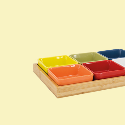 Sechs bunte, quadratische Keramikschalen in gelb, orange, grün, rot, blau und weiss in einem Holztablett.