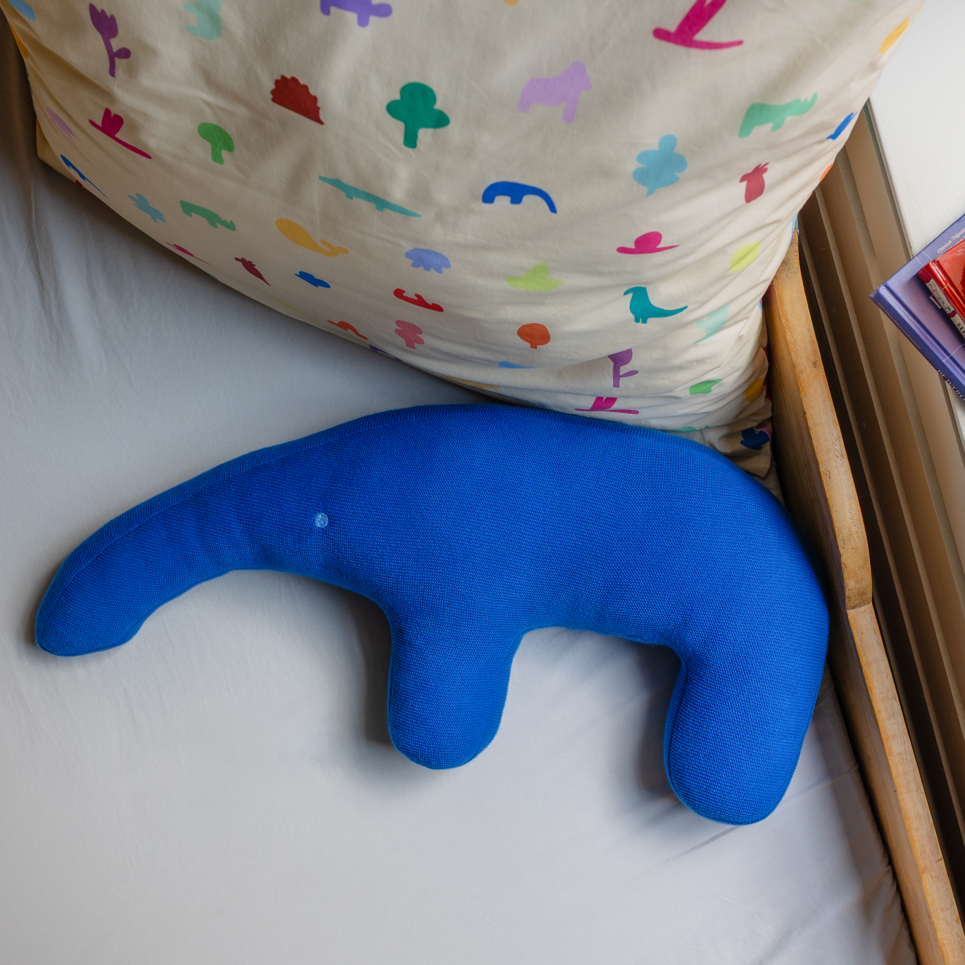 Blauer, liegender Kuscheltier-Ameisenbär Edgar mit Rüssel und Beinen. Das Kissen hat ein Auge.
