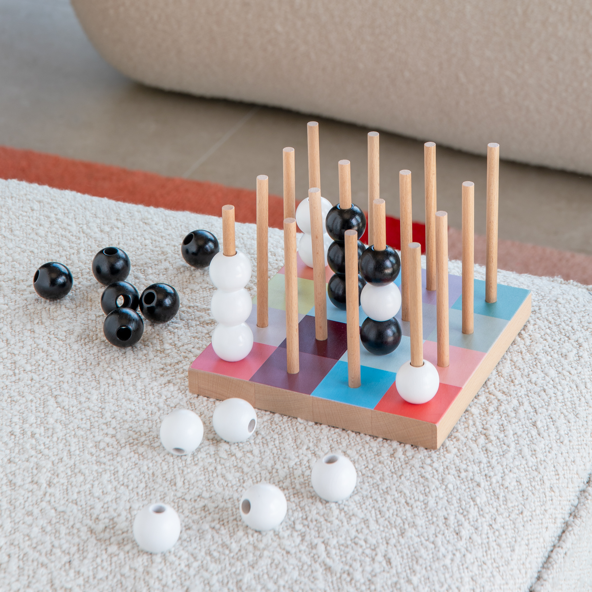 Gros plan sur le jeu de société SOGO, avec ses tiges en bois et ses billes noires et blanches disposées sur un plateau de jeu coloré.