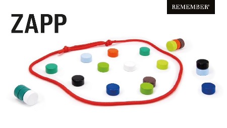 Bunte Spielsteine und eine rote Schnur auf weißem Grund. Die Schnur liegt lose in unregelmäßiger Form, darin und darum viele flache, runde Steine in Farben wie Grün, Blau, Orange, Schwarz und Weiß. Einige sind gestapelt.