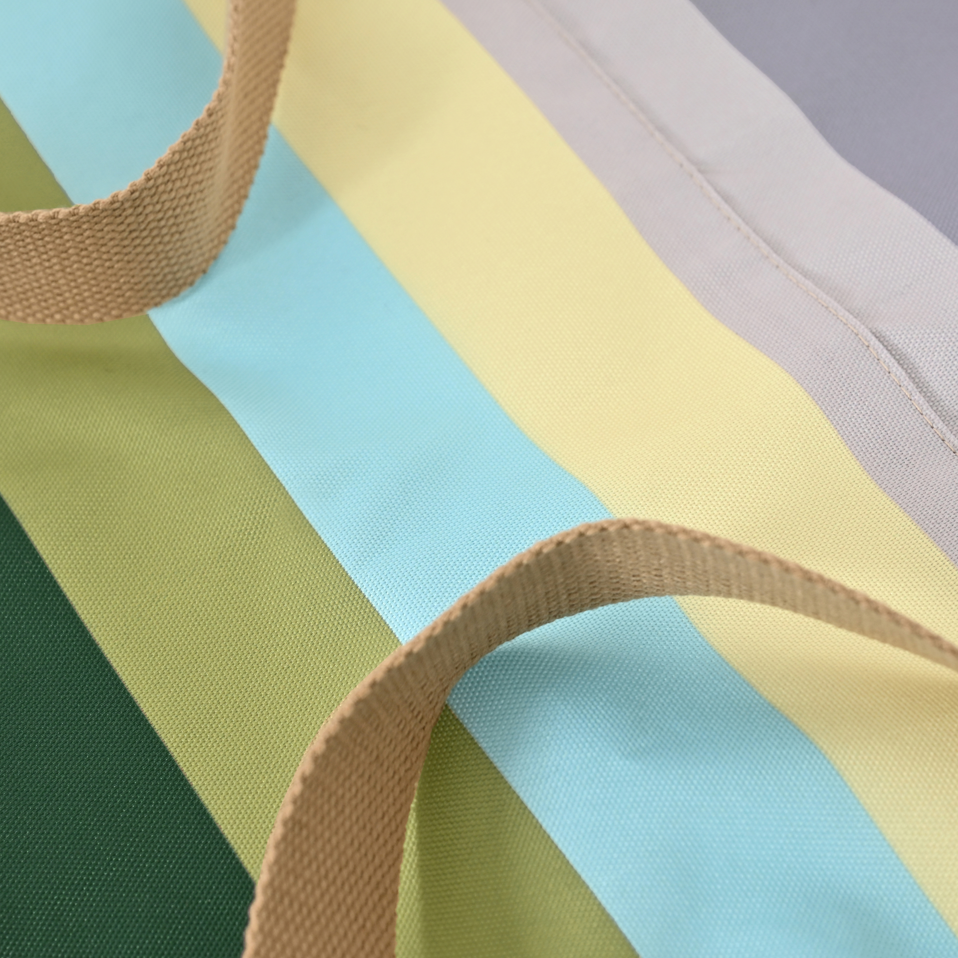 Gros plan sur une couverture pour chien d'extérieur Ronja à rayures colorées vert foncé, olive, bleu clair, jaune pâle et gris clair. Deux sangles de transport marron se croisent. Polyester, coutures visibles.