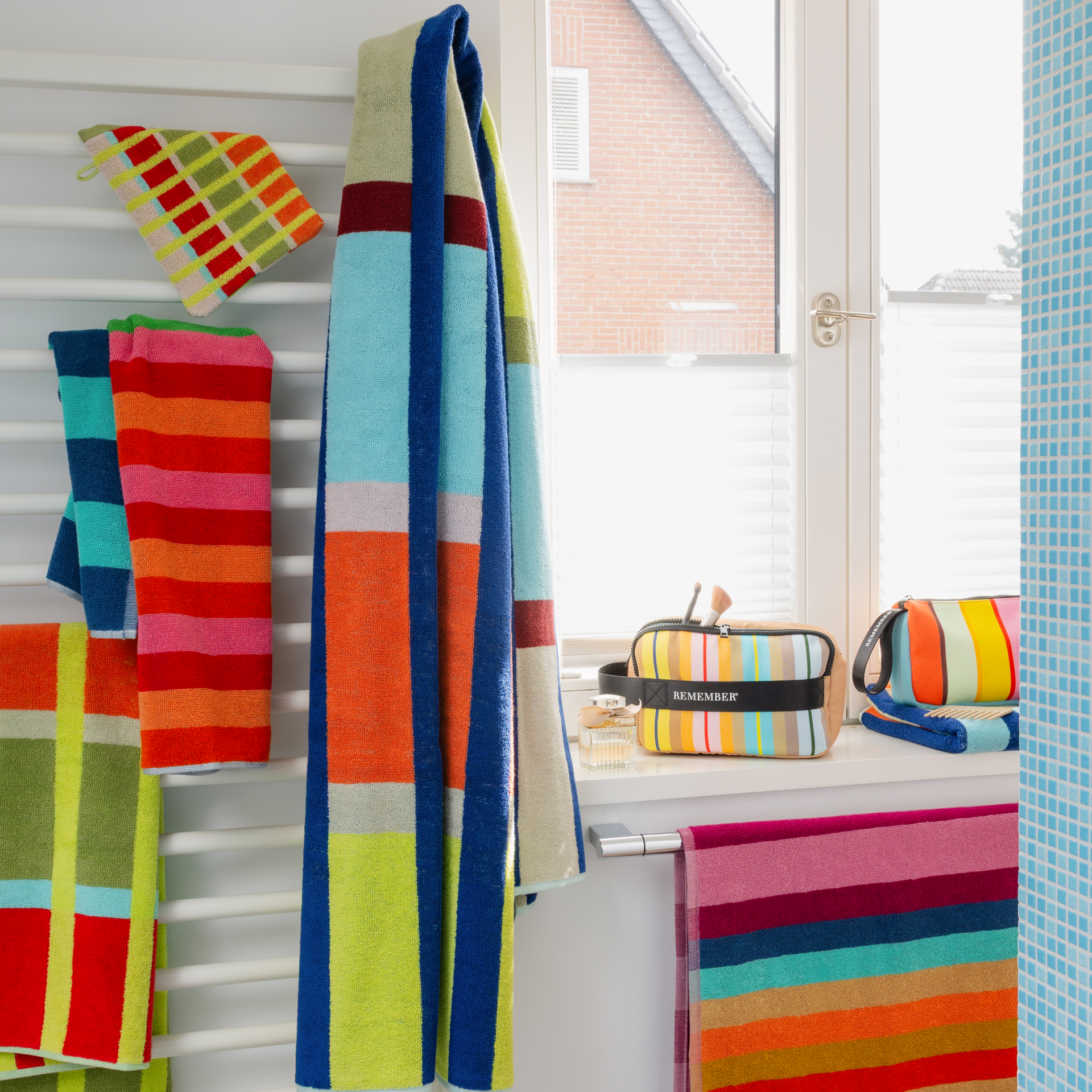 Serviette de bain Yoku à carreaux colorés. Larges rayures verticales bleu foncé croisées avec des bandes horizontales blanches, bleu clair, jaunes, rouge-orange et vert-beige. Coton moelleux, très grande et absorbante.