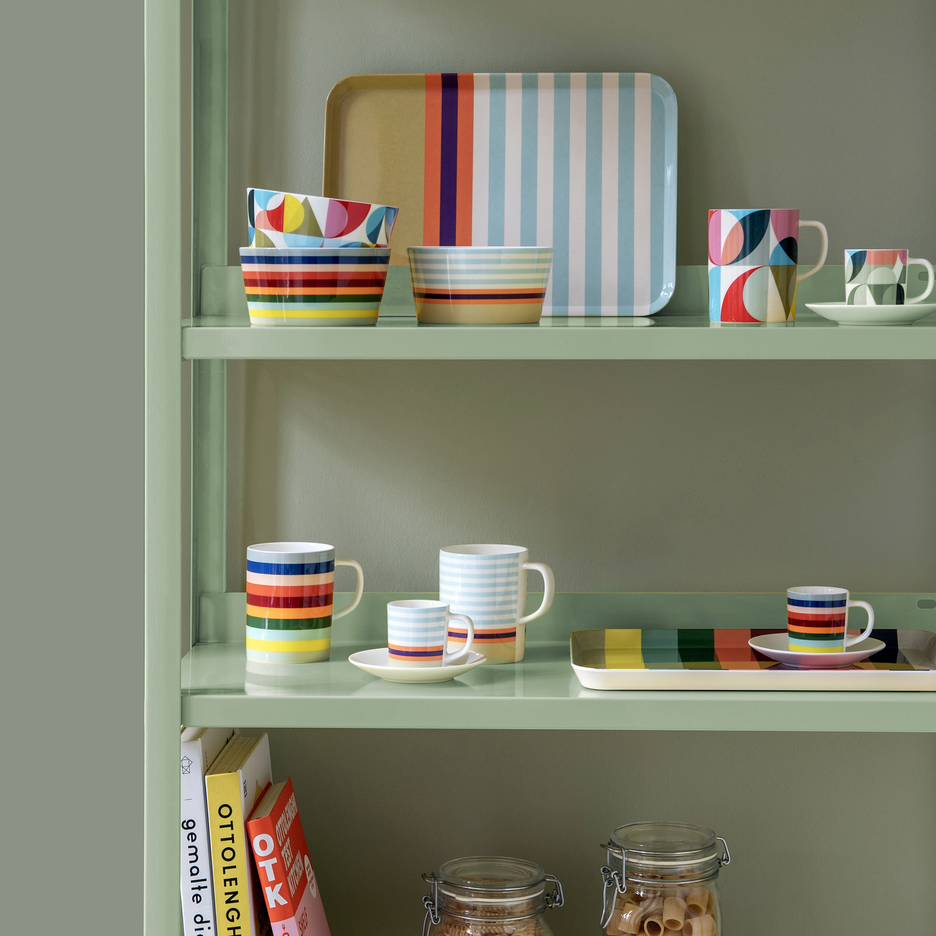 Pastellfarbenes Regal mit Geschirr und dem Mini-Tablett „Positano“. Tassen, Schalen und das Tablett verfügen über verschiedene Muster und Designs.
