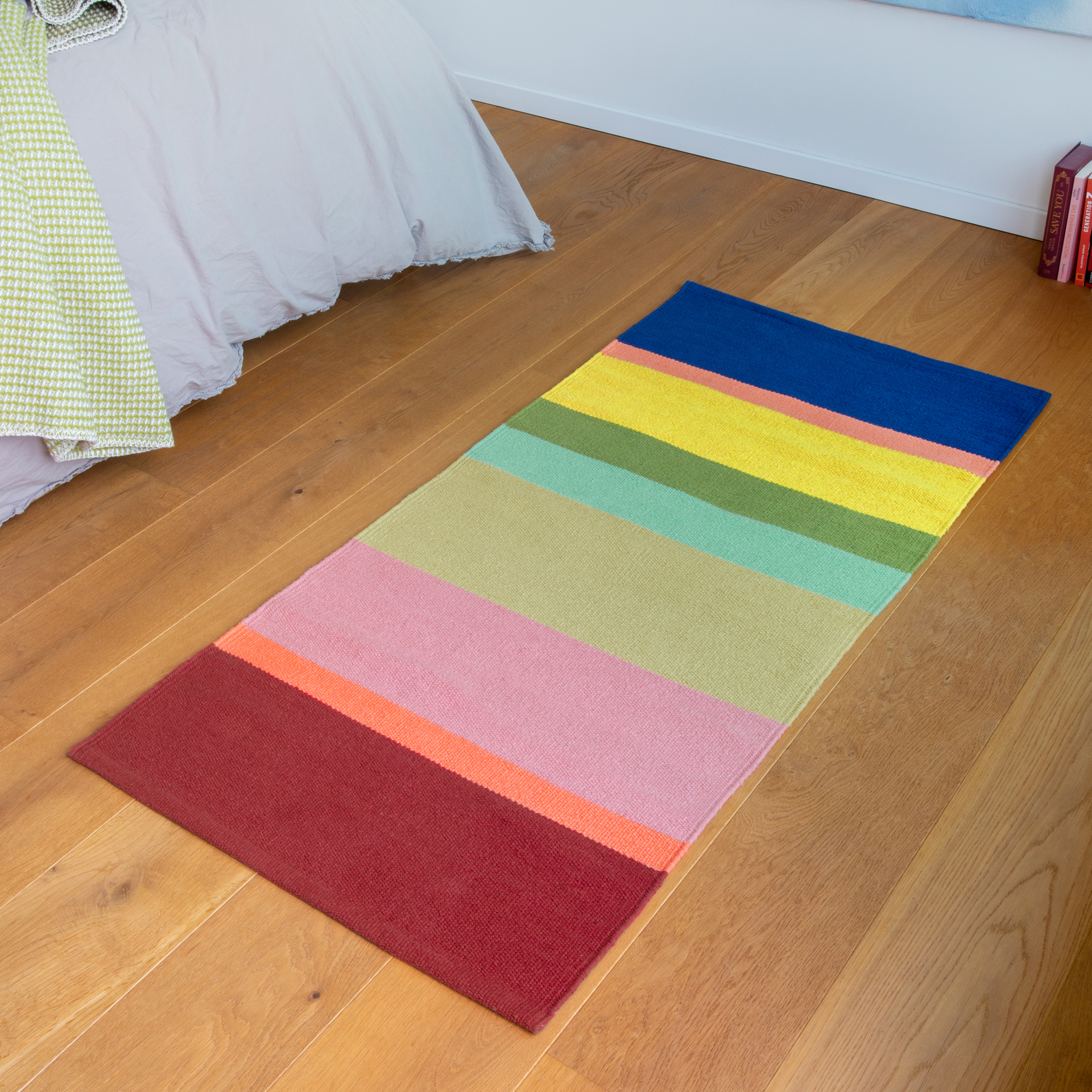 Un tapis de passage 'Riva kurz' avec des rayures colorées en rouge, orange, rose, vert et bleu sur un fond blanc.